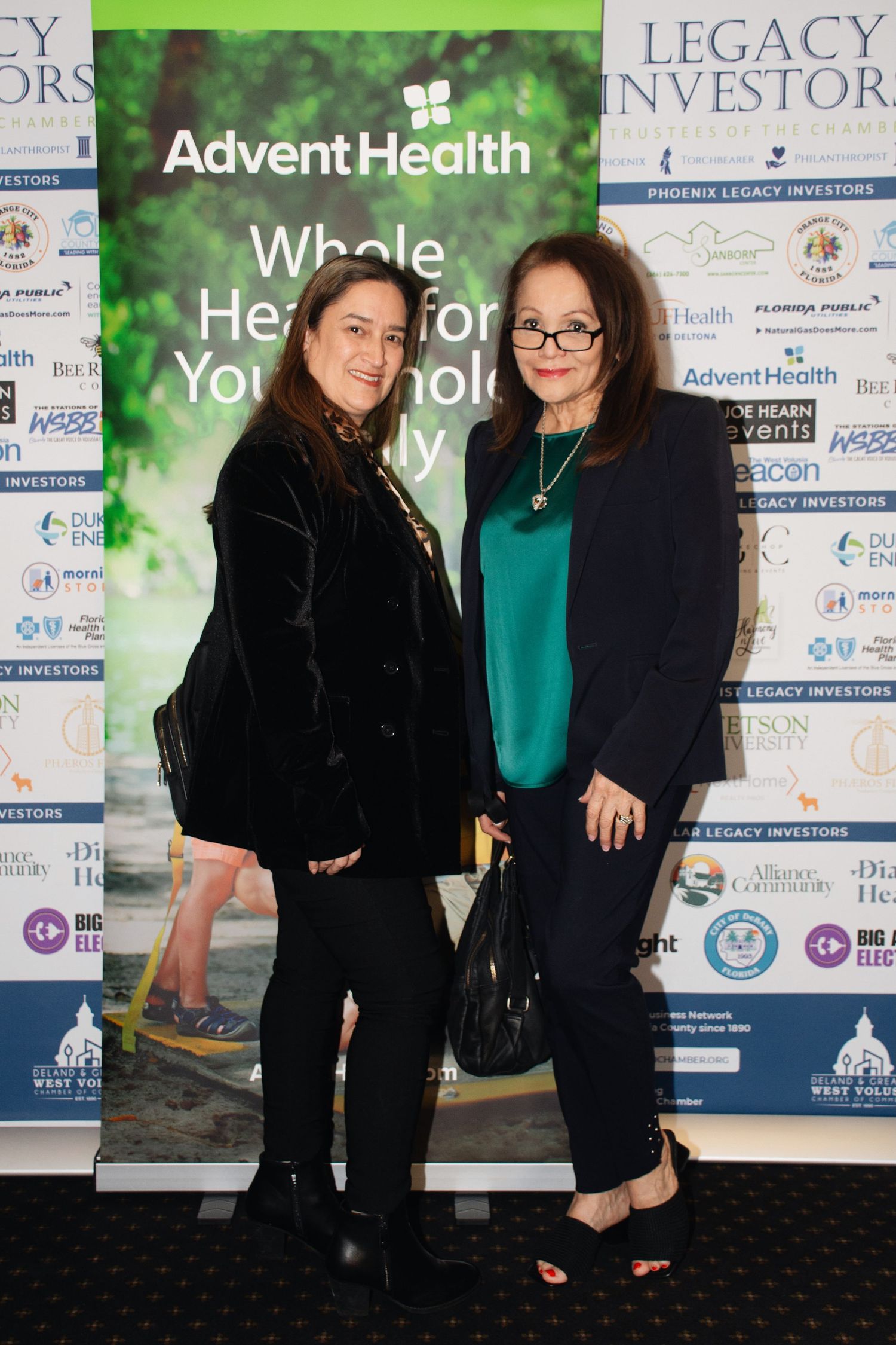 Professional event photos showing attendees posing in front of branded sponsor walls with company logos and banners.