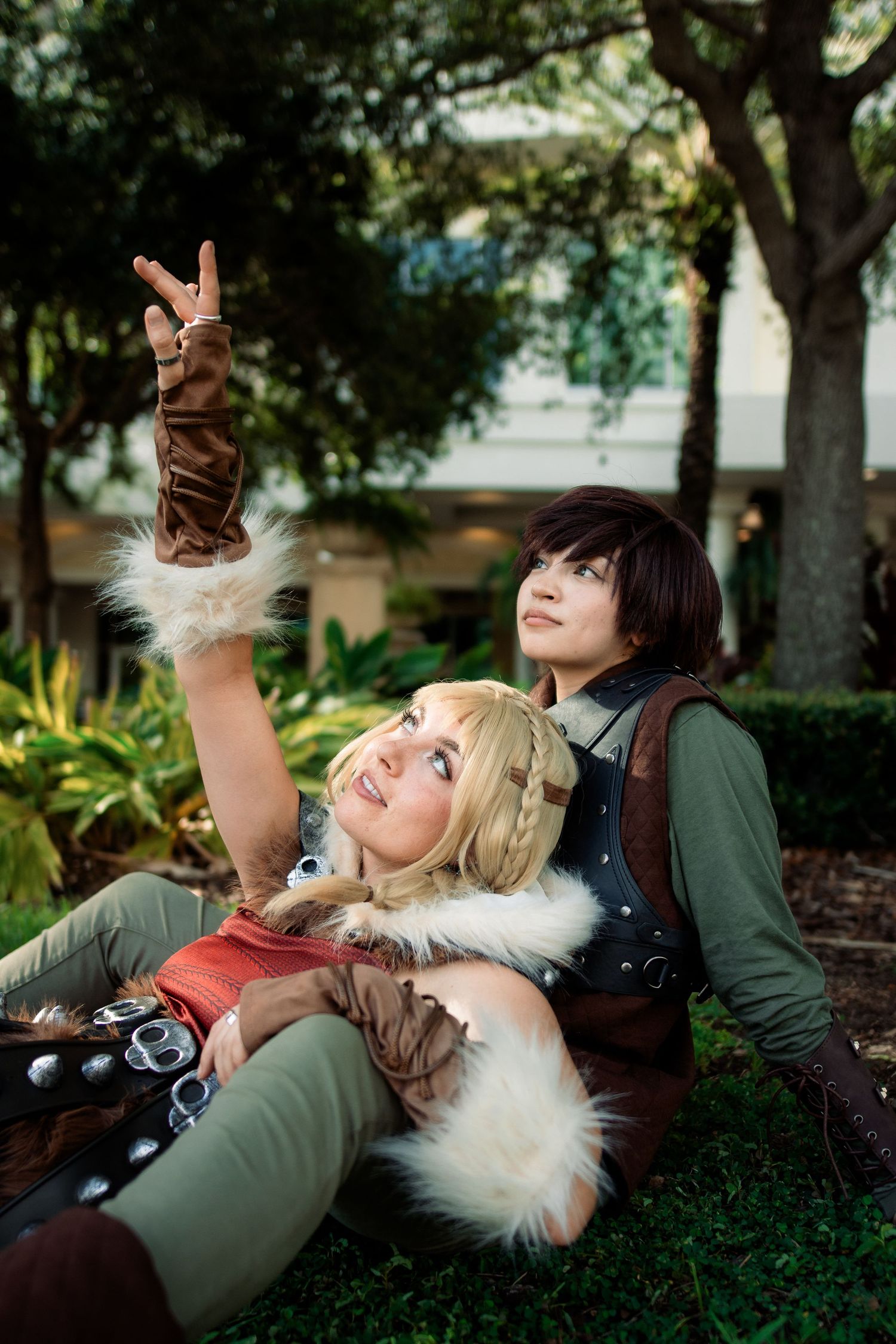Two cosplayers dressed as Hiccup and Astrid from How to Train Your Dragon posing outdoors at a convention.