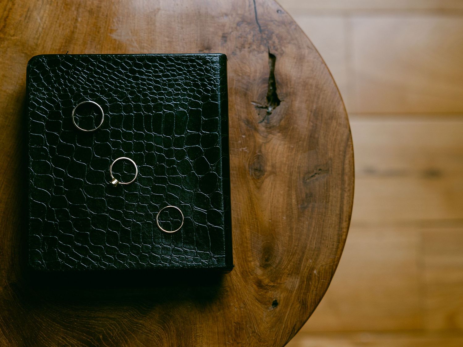 Rustic wooden table surface with dark leather wallets arranged in a row against a warm brown background micro wedding planning tips for 2026