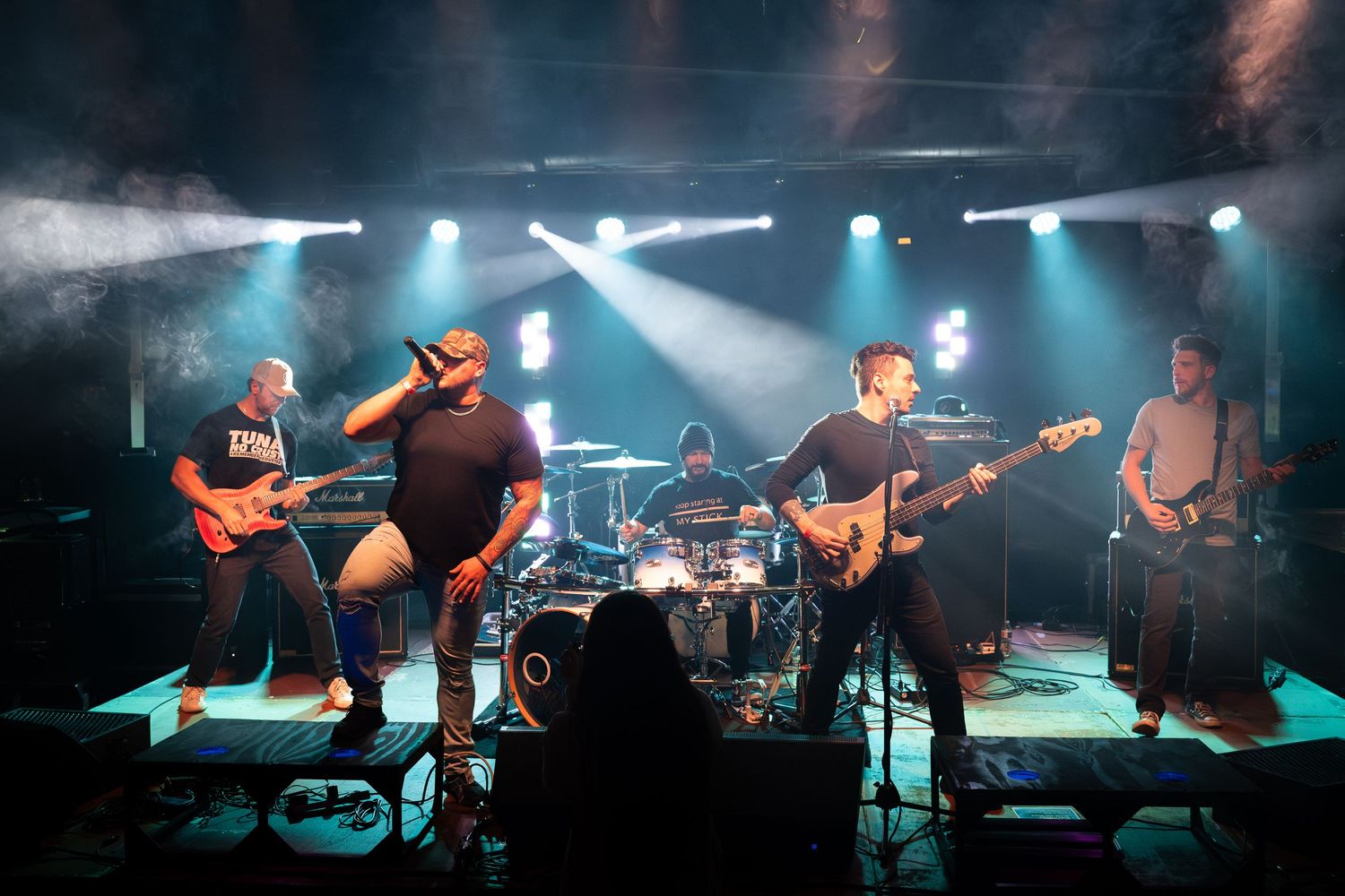 Concert performers on stage with dramatic blue lighting and fog effects during a live music performance.