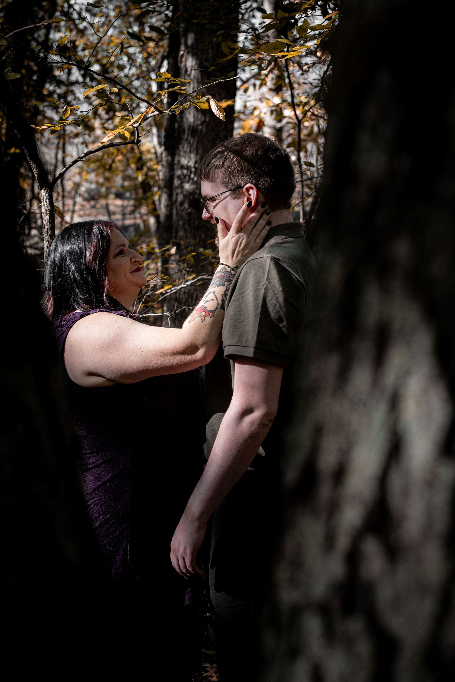 Two dancers perform an intimate dance sequence in a forest setting with autumn trees in the background.