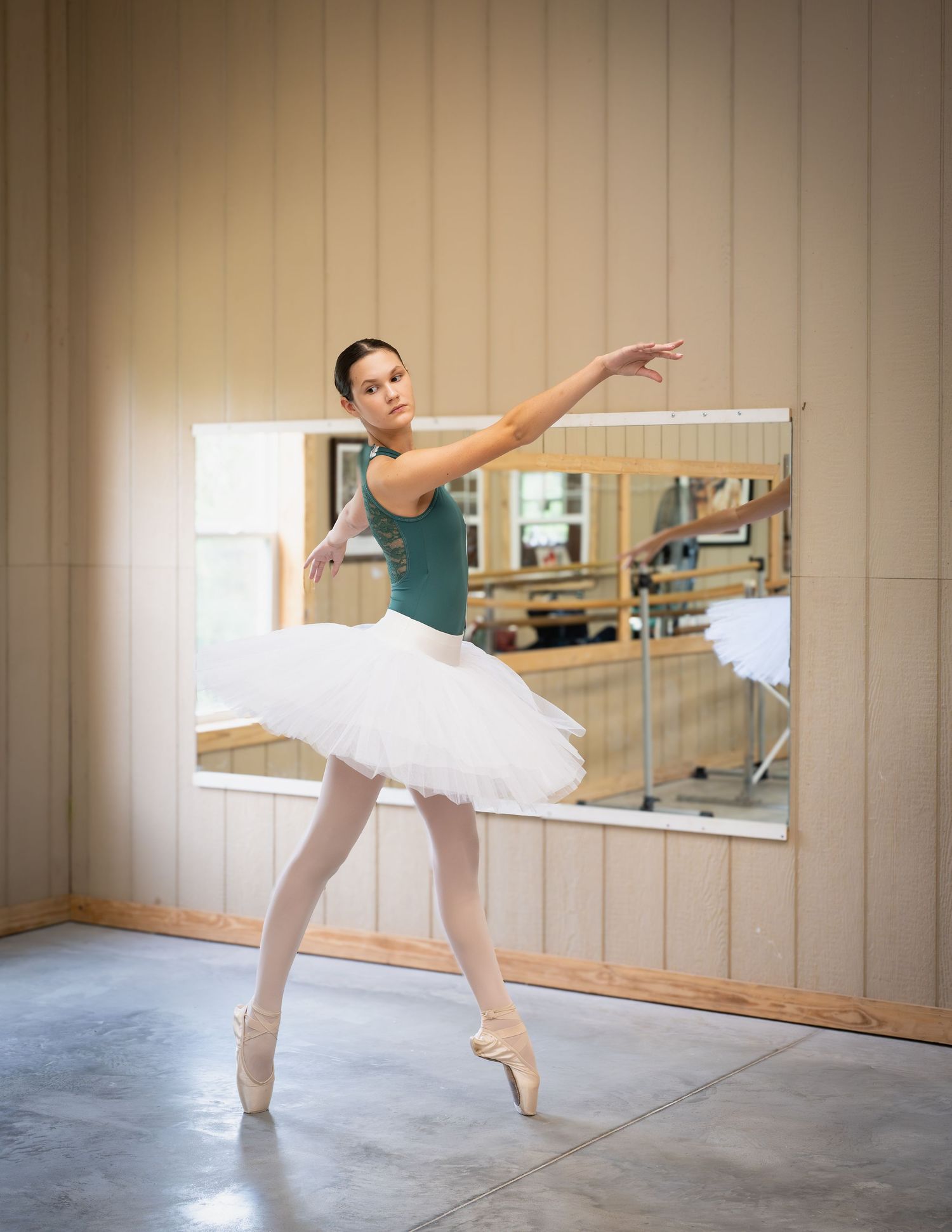 Ballet dancer in white tutu practices graceful arabesque poses in a mirrored dance studio.
