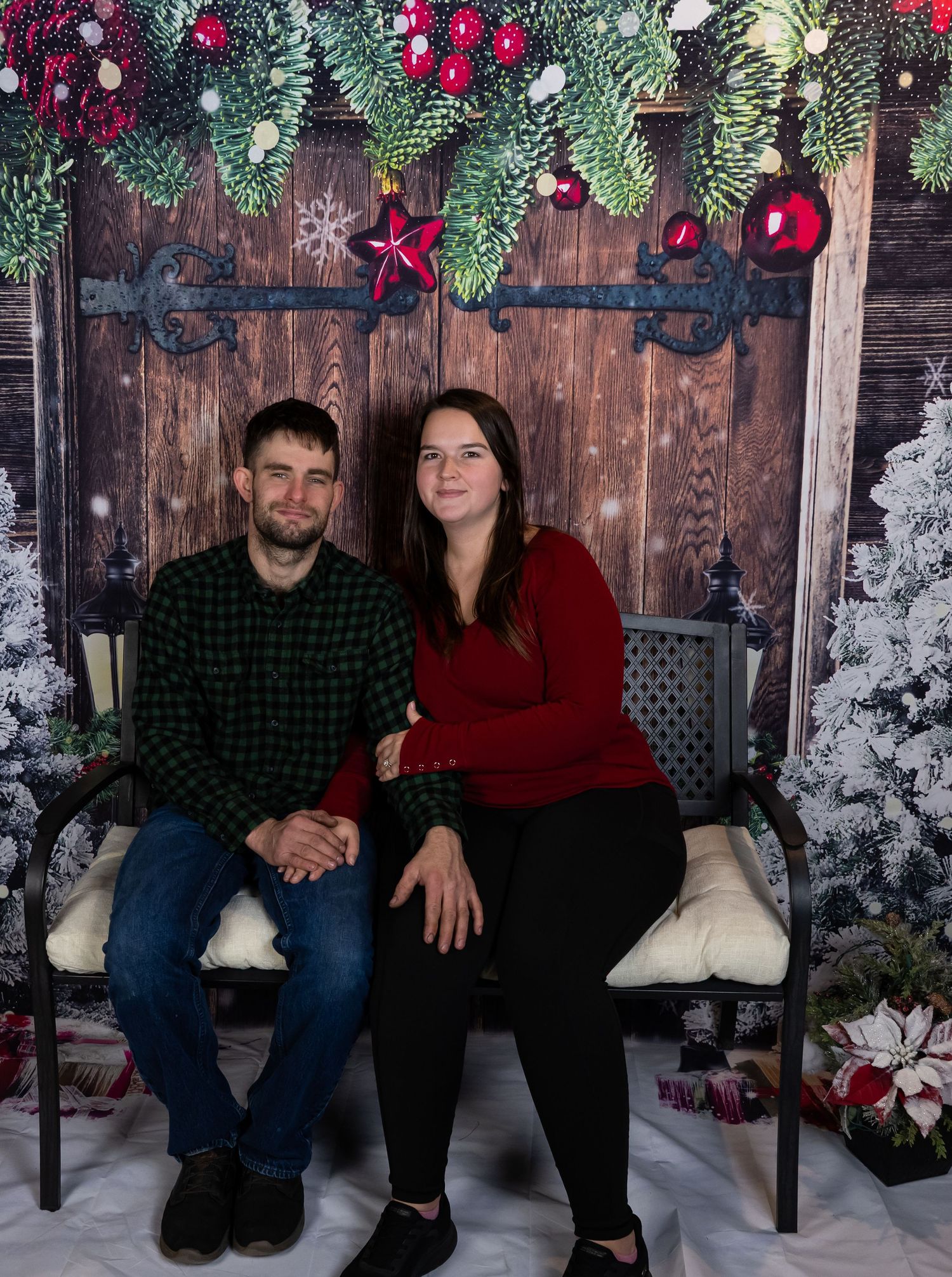 Festive Christmas portrait setting with rustic wood wall and decorated evergreen garland.