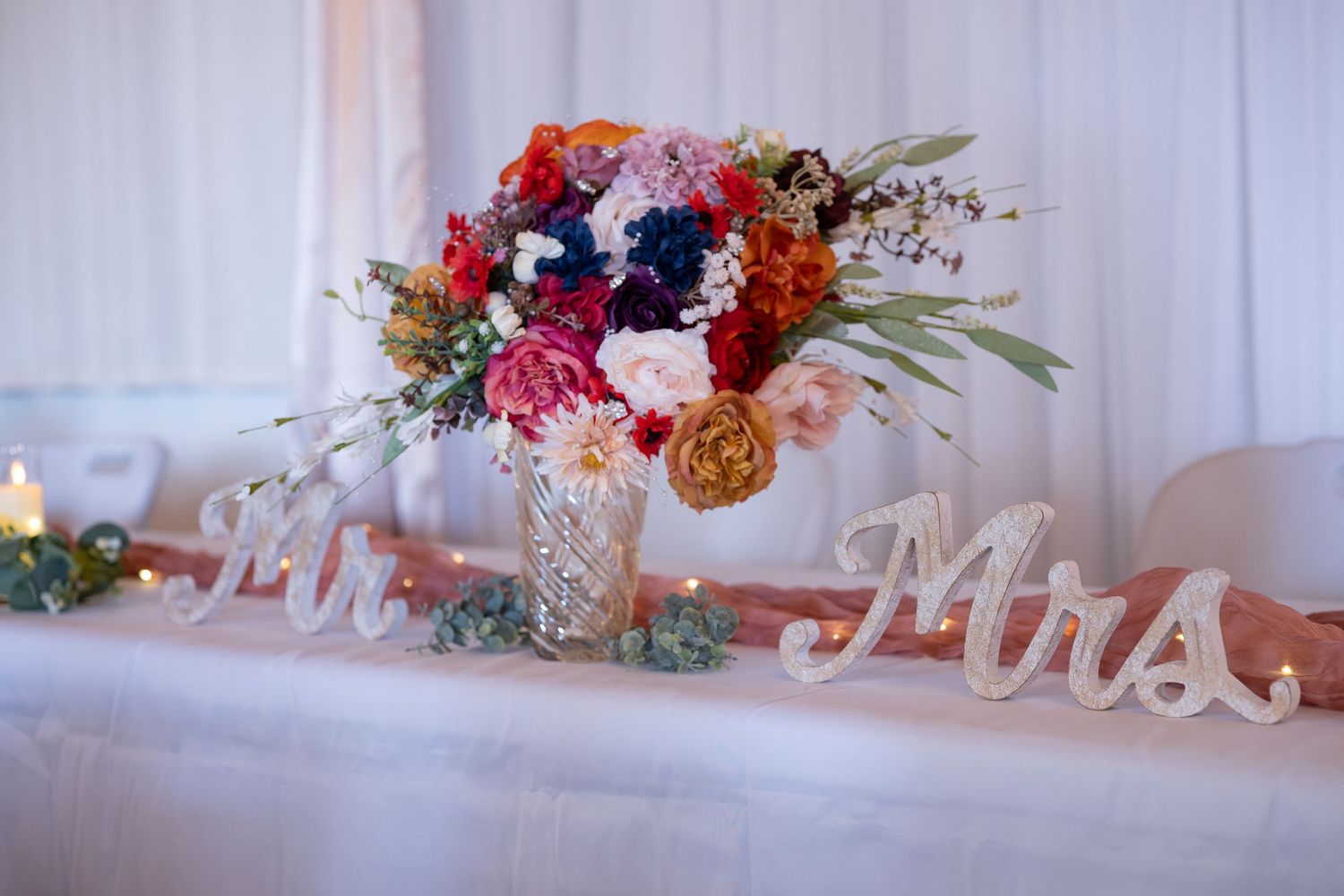Reception table with Mr. and Mrs. signs and vibrant floral centerpieces.