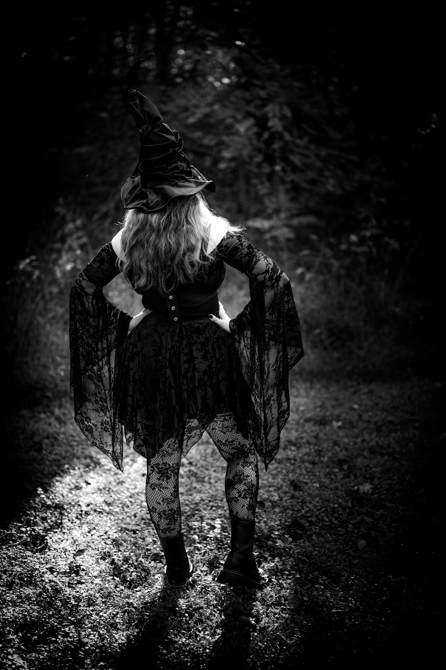 A silhouetted figure stands in a dark forest with dramatic backlighting creating an ethereal glow through trees.