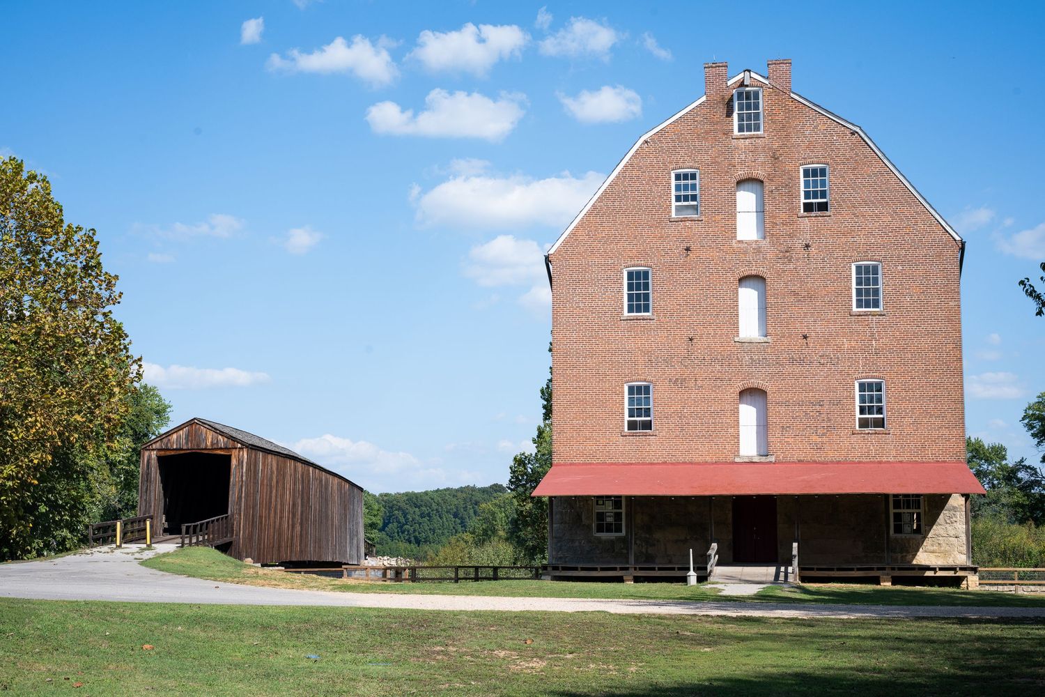 A series of identical red barns with white trim and dormers photographed from different angles against a blue sky.