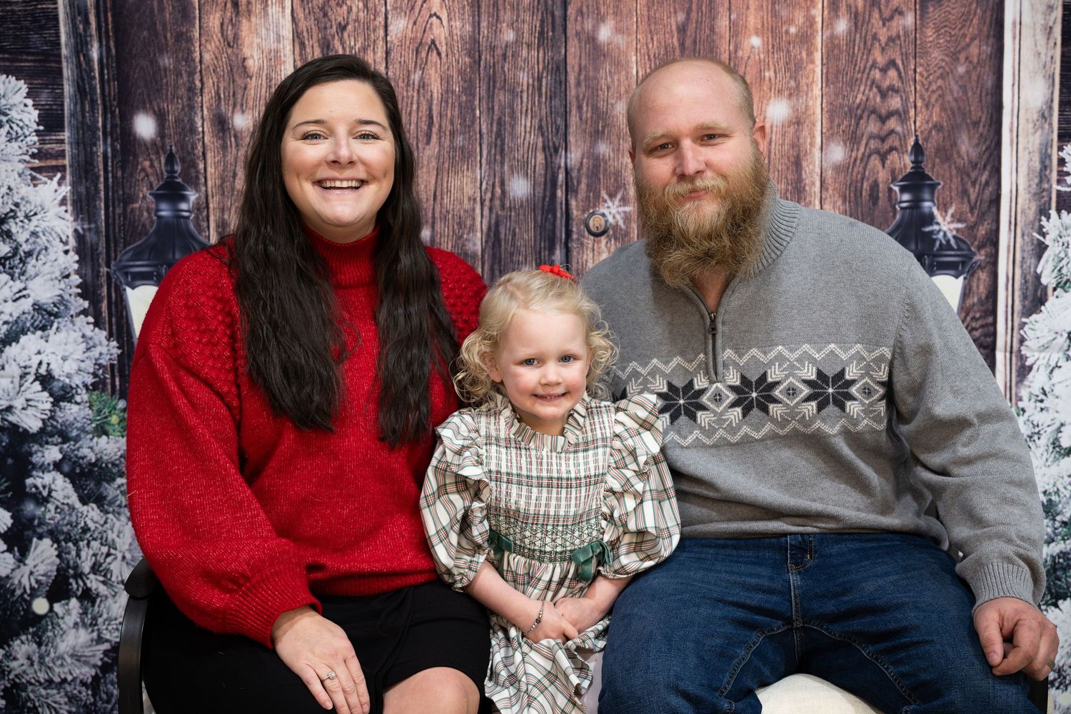 Holiday family portrait setting with decorated evergreen garland and wooden backdrop.