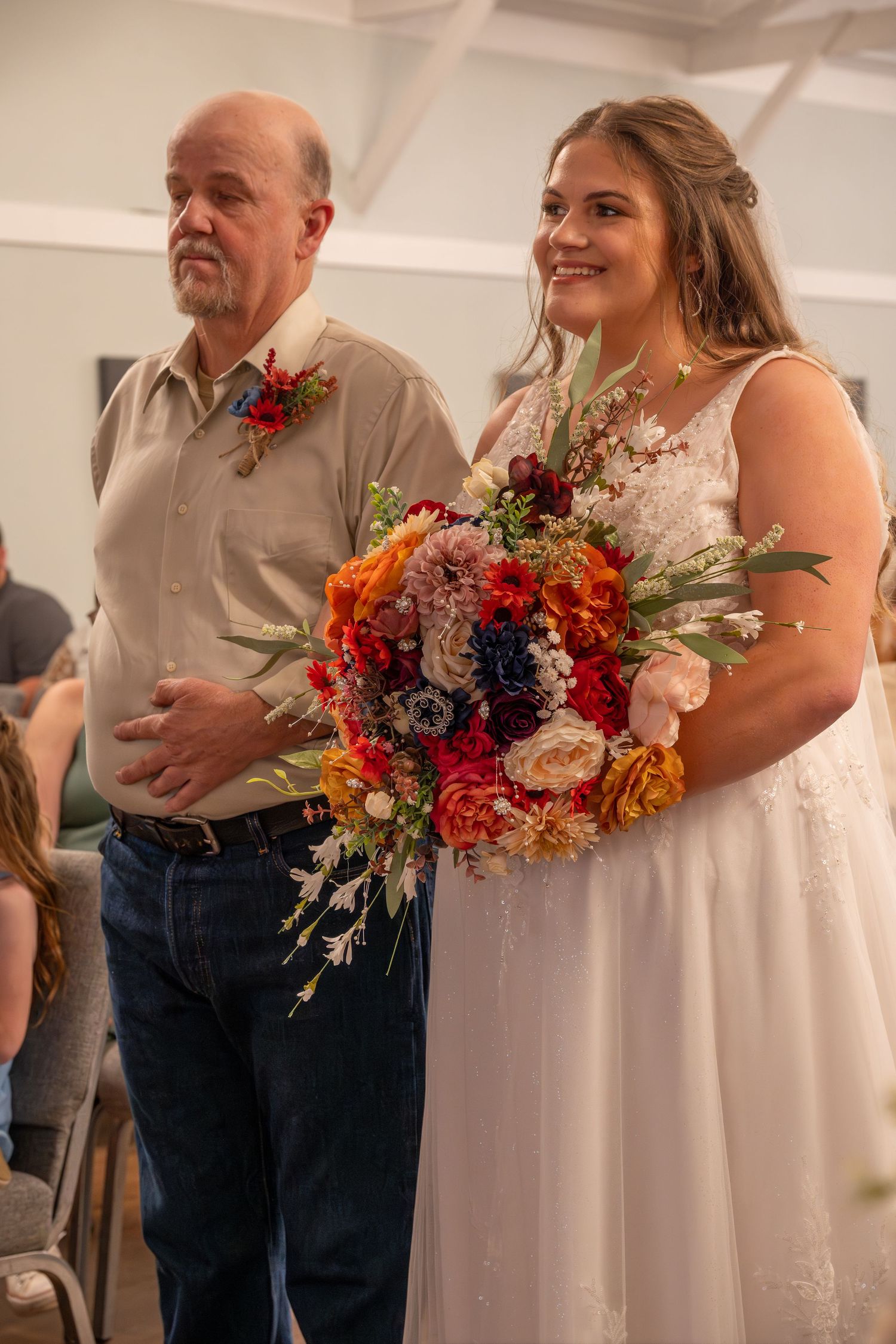 Wedding party holding vibrant fall-colored bouquets against white walls.