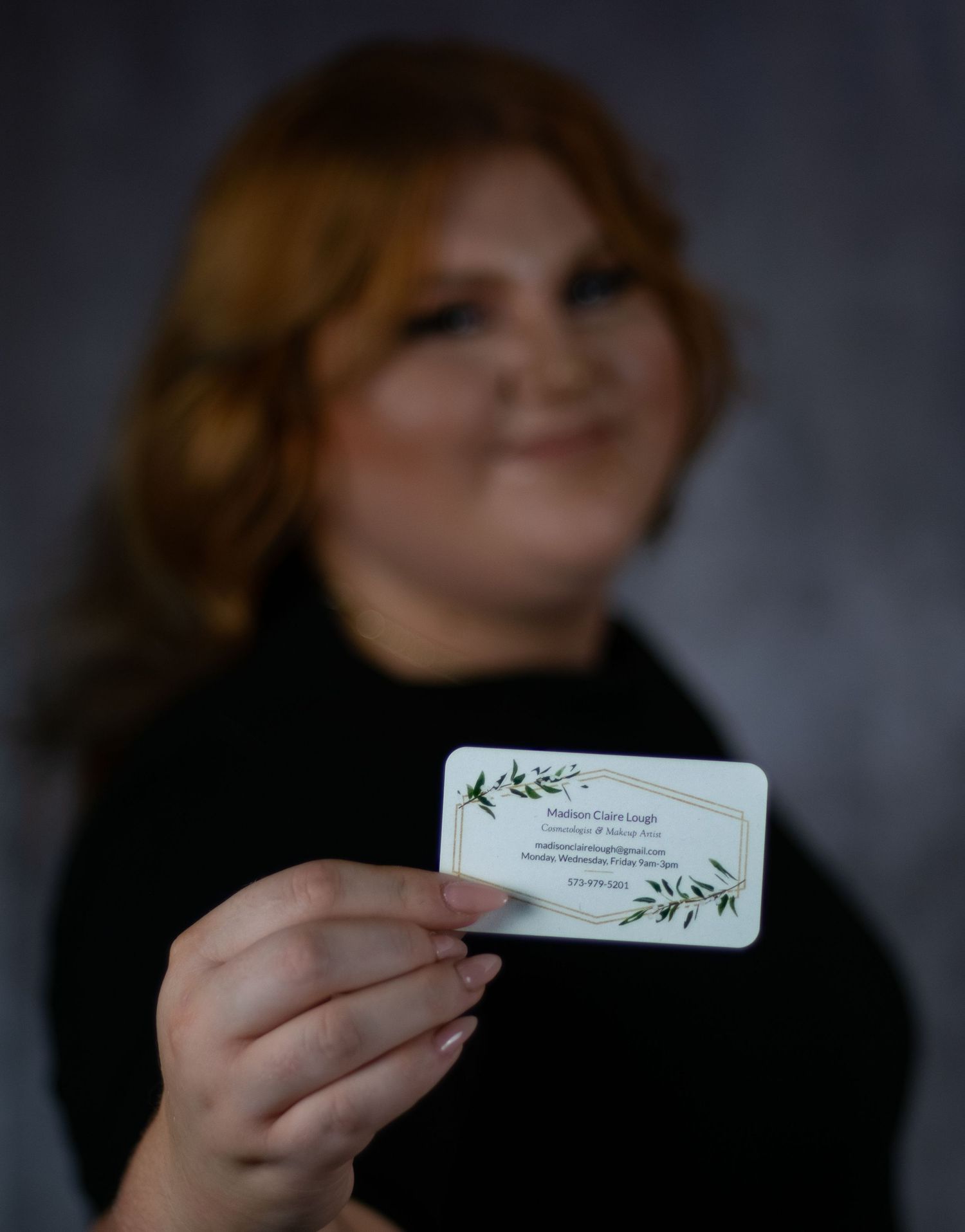 A person with reddish hair holds up a white business card against a dark background in a sequence of photos.