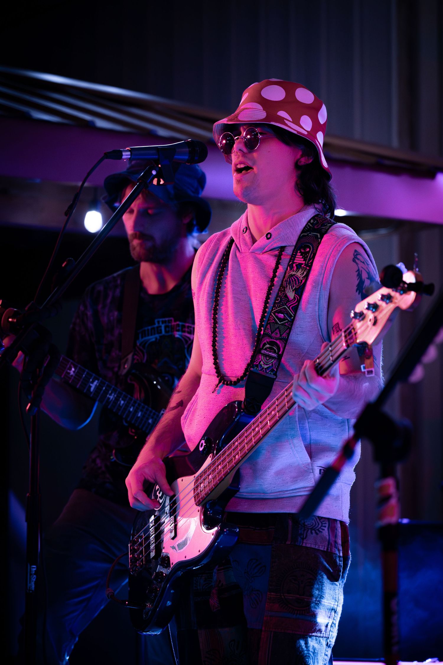 Musicians perform on stage bathed in vibrant purple and blue lighting during a live concert performance.