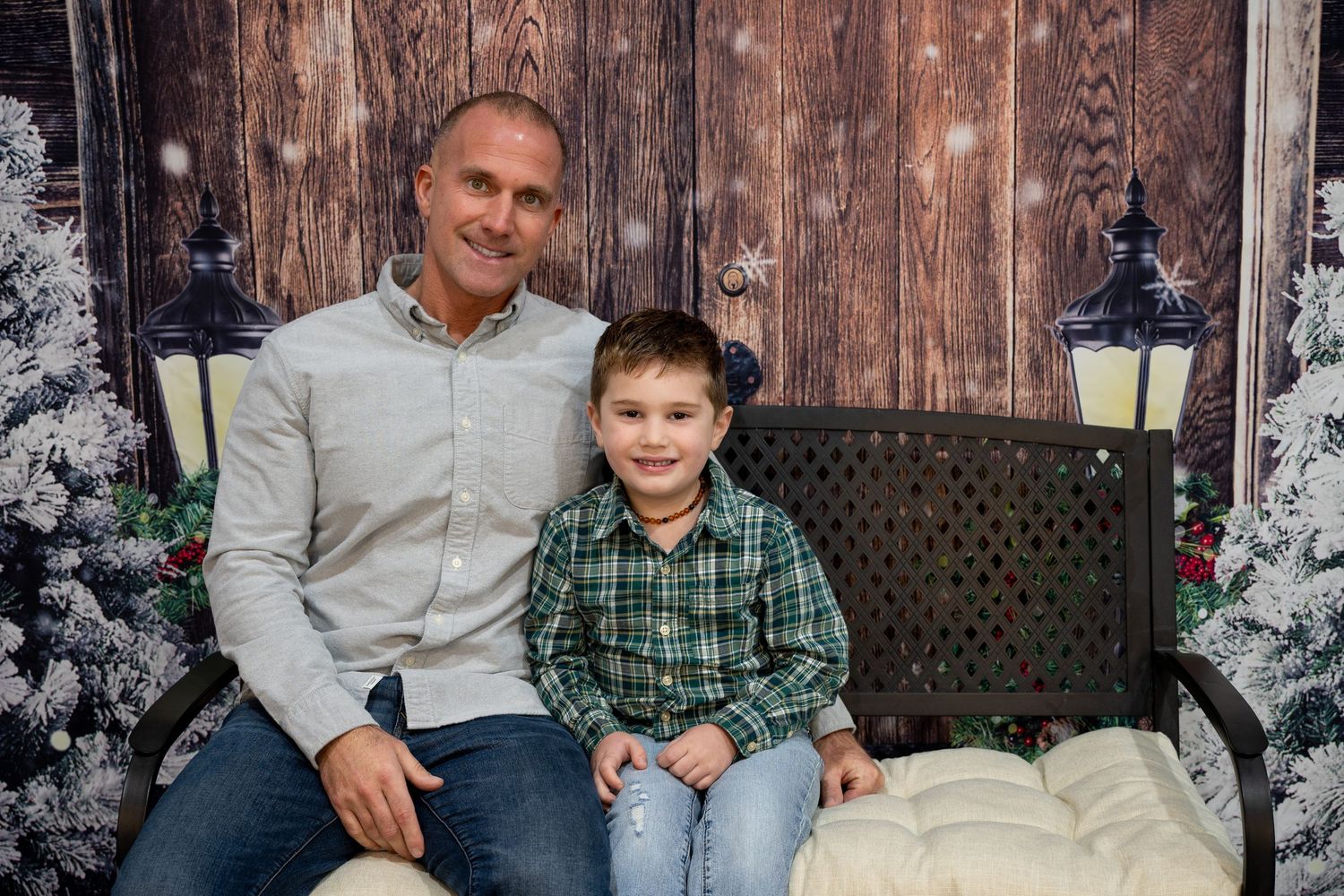 Family members sit together on wooden steps in front of a rustic barn wall wearing casual winter attire.