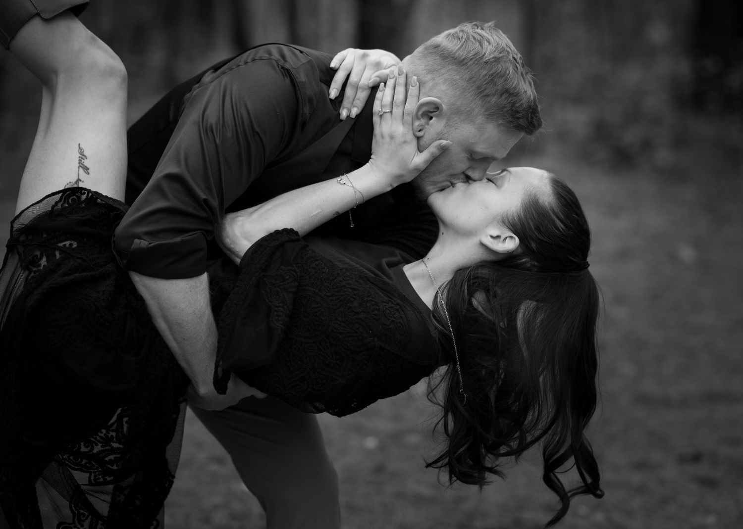 A romantic black and white photograph captures an intimate dance dip moment between two people outdoors.