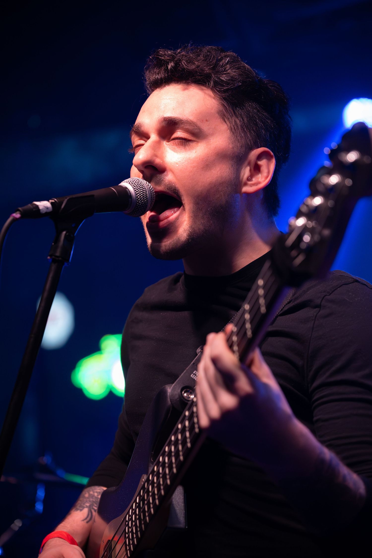 Close-up shots of musician playing bass guitar against vibrant blue stage lighting.