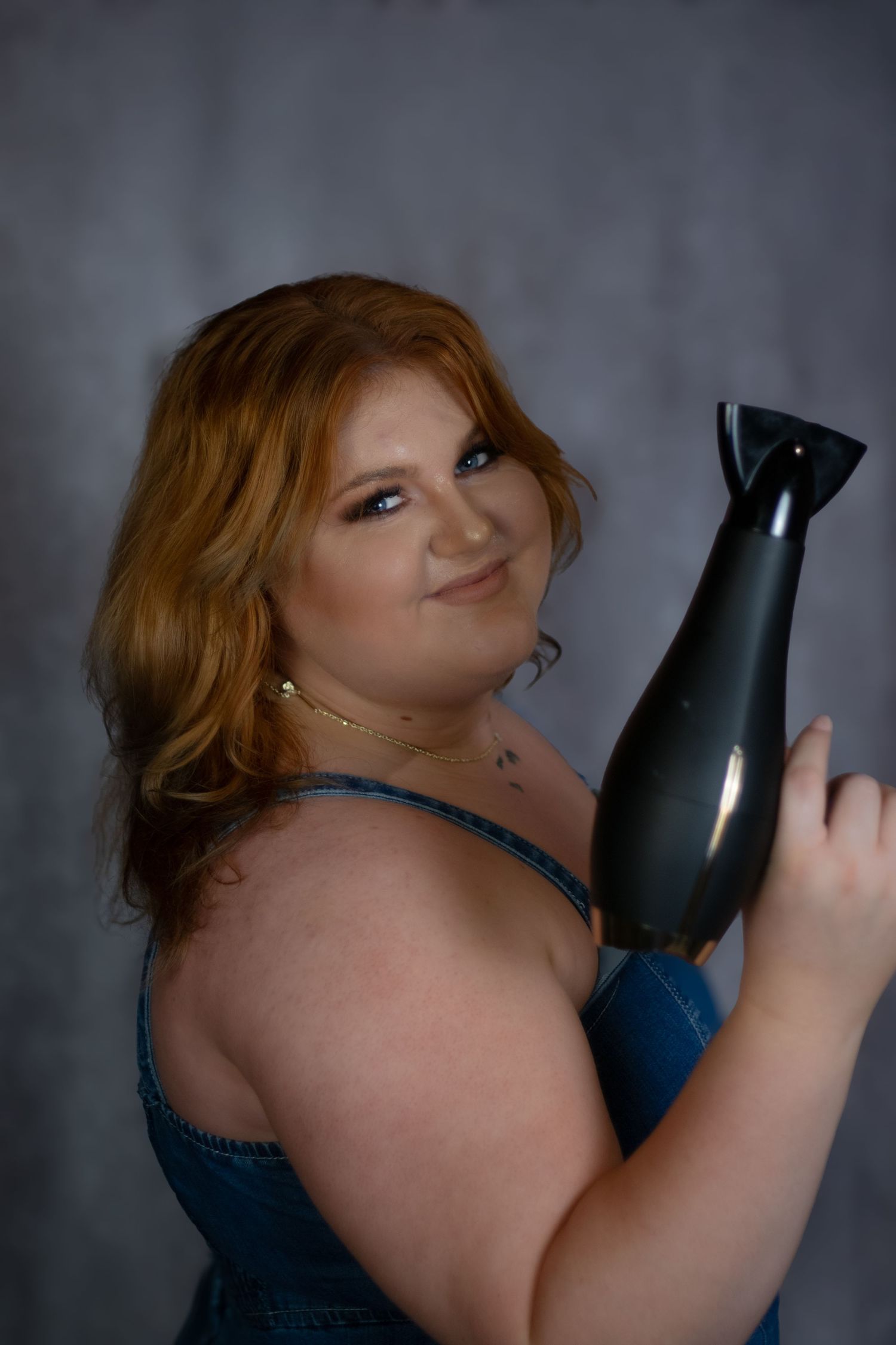A series of photos showing someone with red hair posing with a black hair dryer against a dark background.