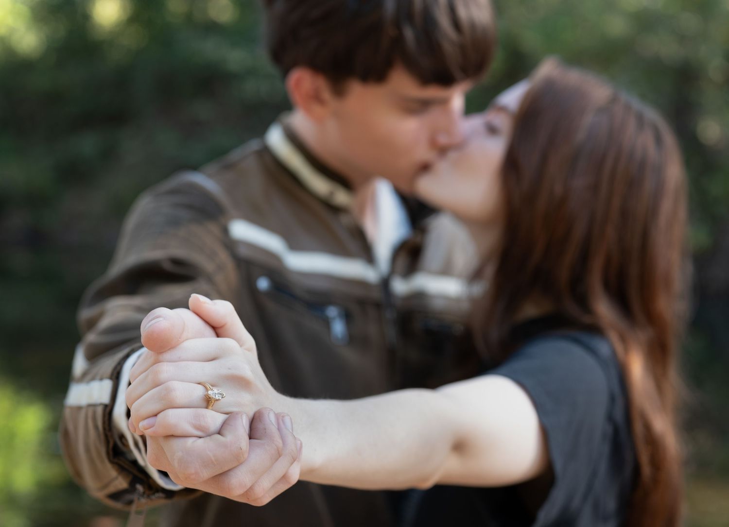 A couple dances together in a park setting during a romantic outdoor photo session.