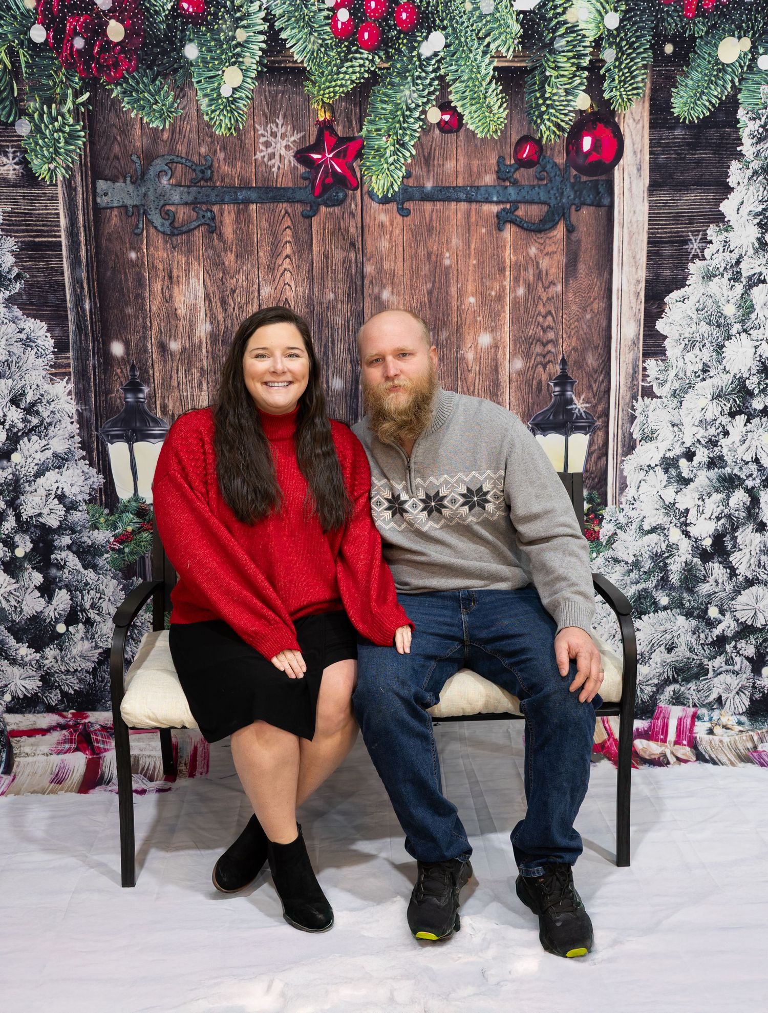 Christmas portrait scene with evergreen garland, red ornaments and wooden backdrop.