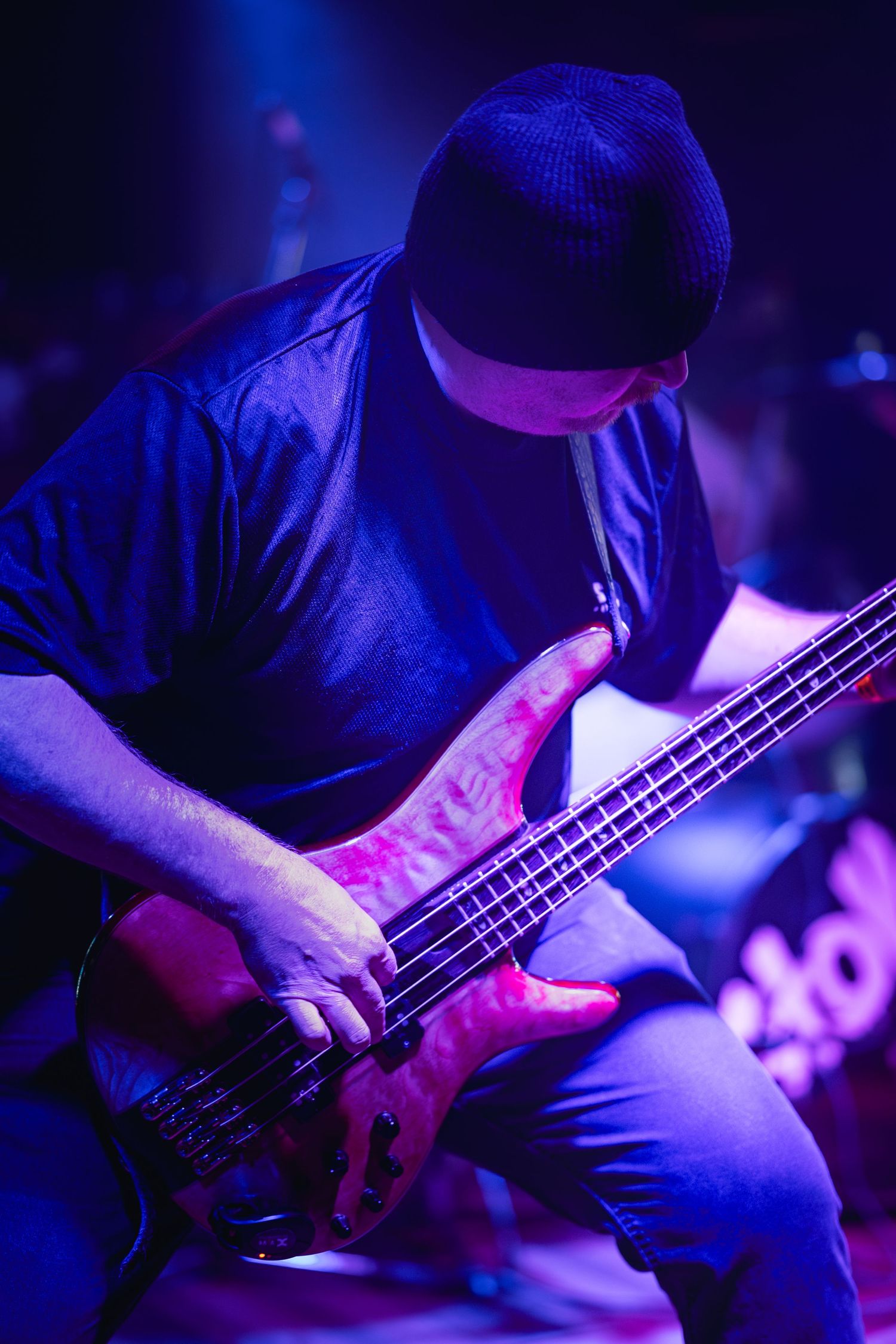 Close-up sequence of musician playing electric bass guitar under dramatic blue and purple stage lighting.