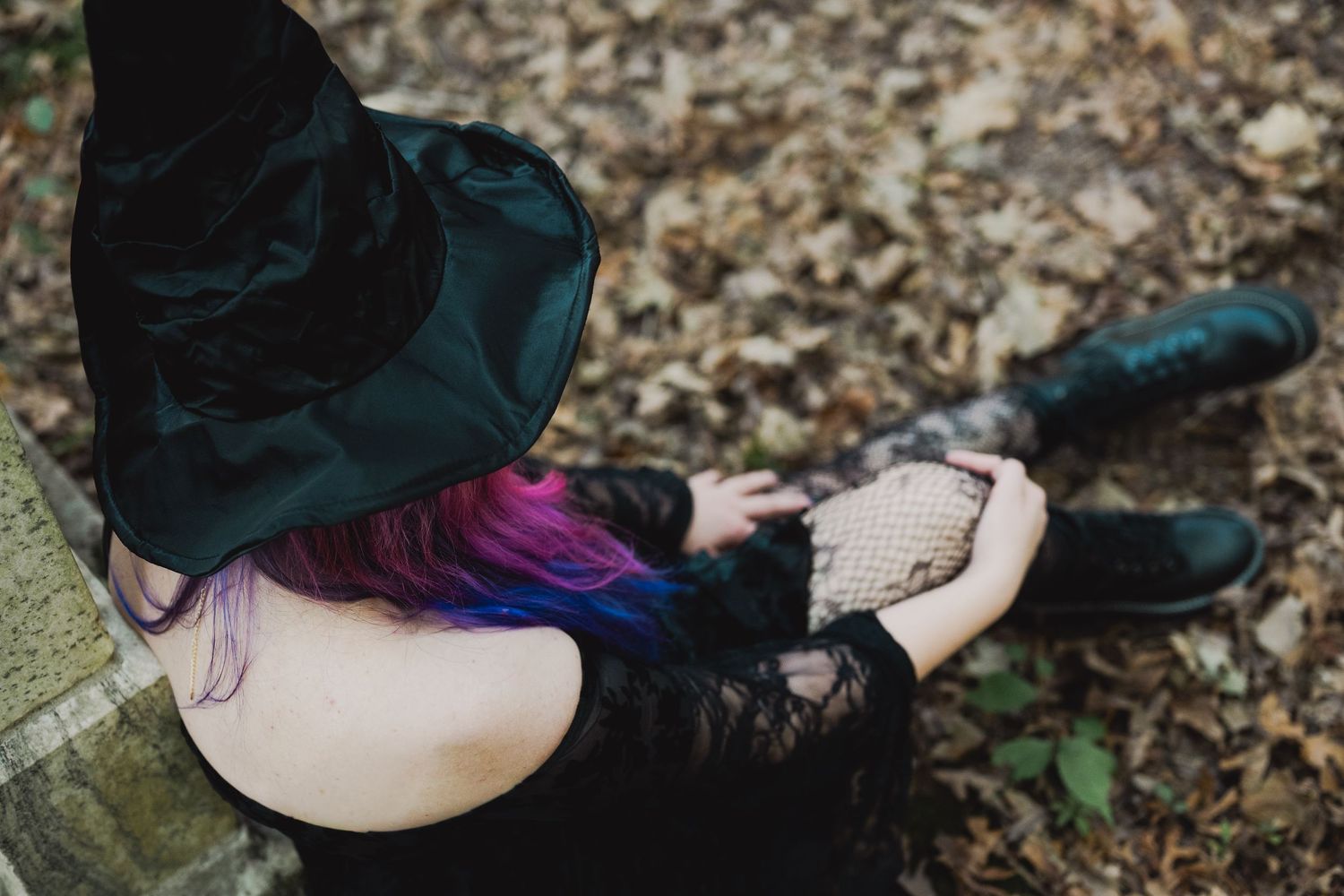 A person in dark clothing lies on autumn leaves in an artistic outdoor photo series.