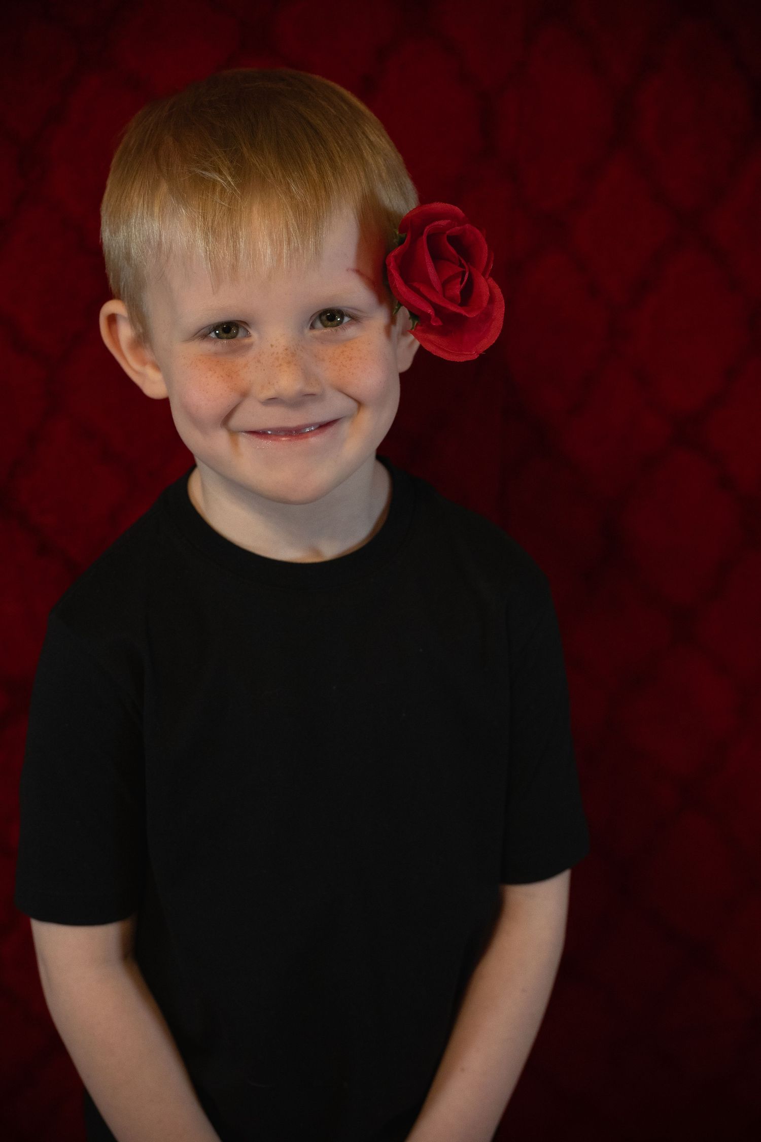 Child wearing a black shirt smiles against a dark red background in a series of portrait photos.