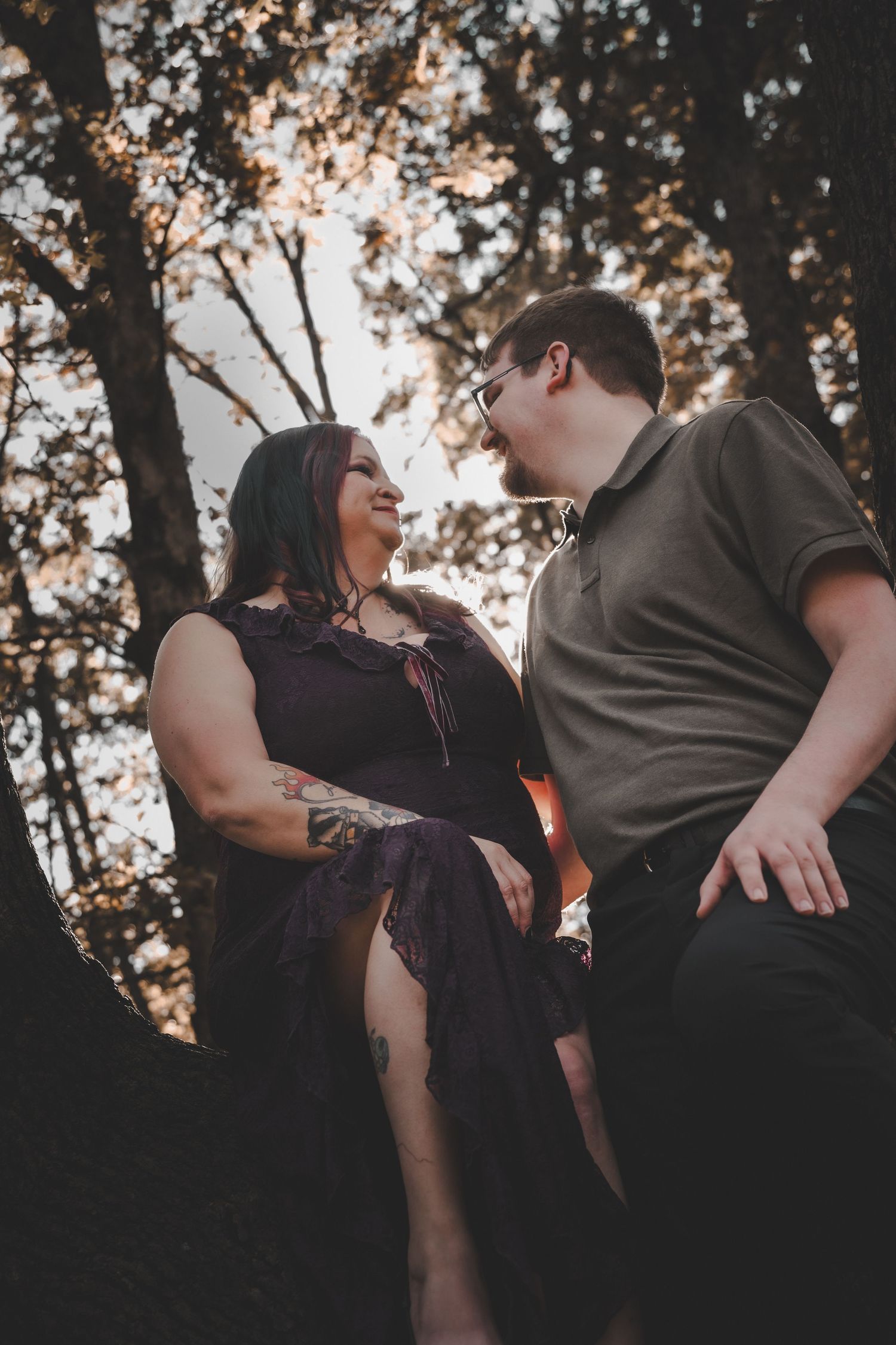 A romantic couple shares a joyful moment together in a forest during golden hour sunset lighting.