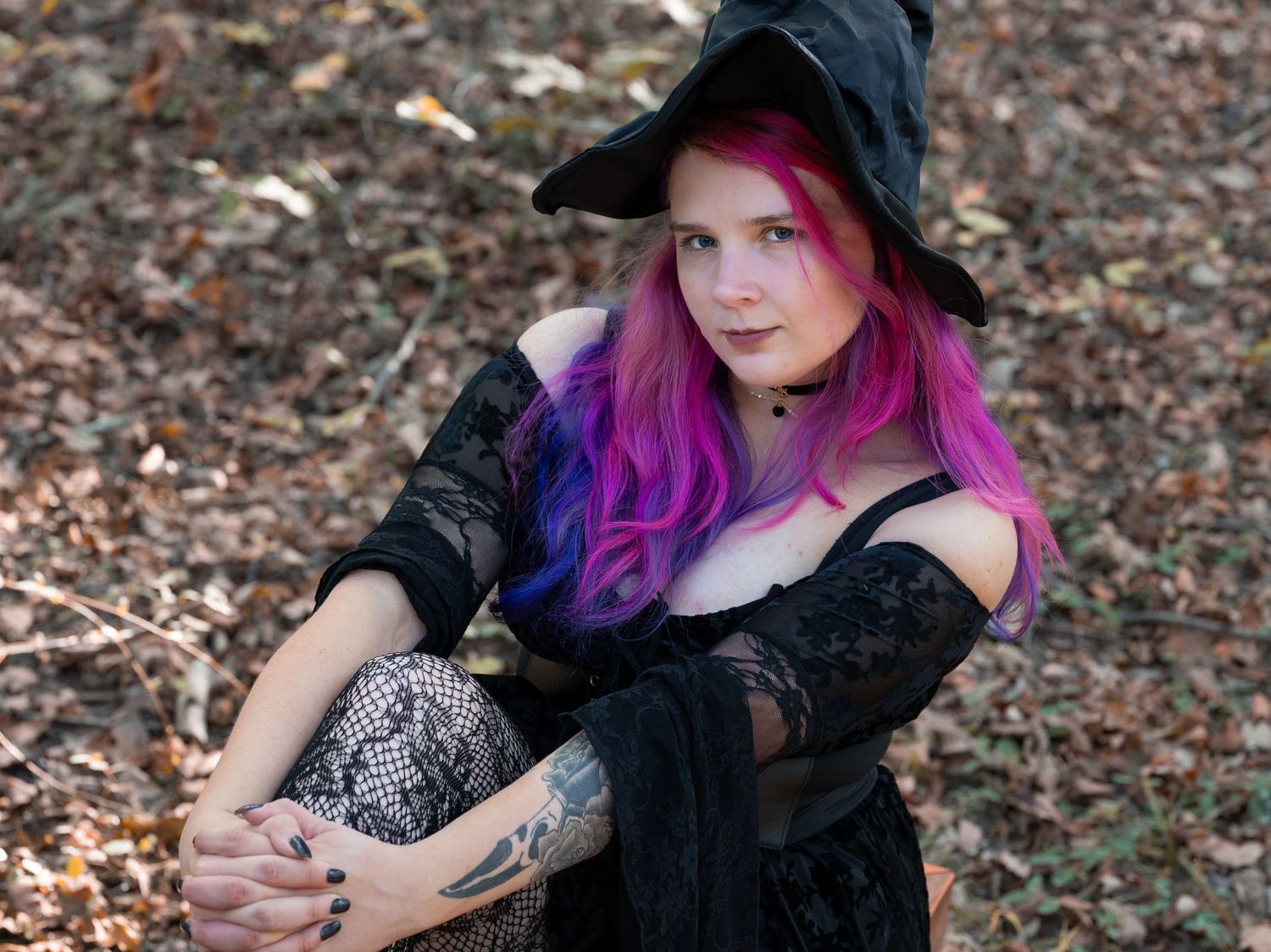 A person with vibrant purple hair wearing a black hat poses on fallen autumn leaves in a series of artistic portraits.