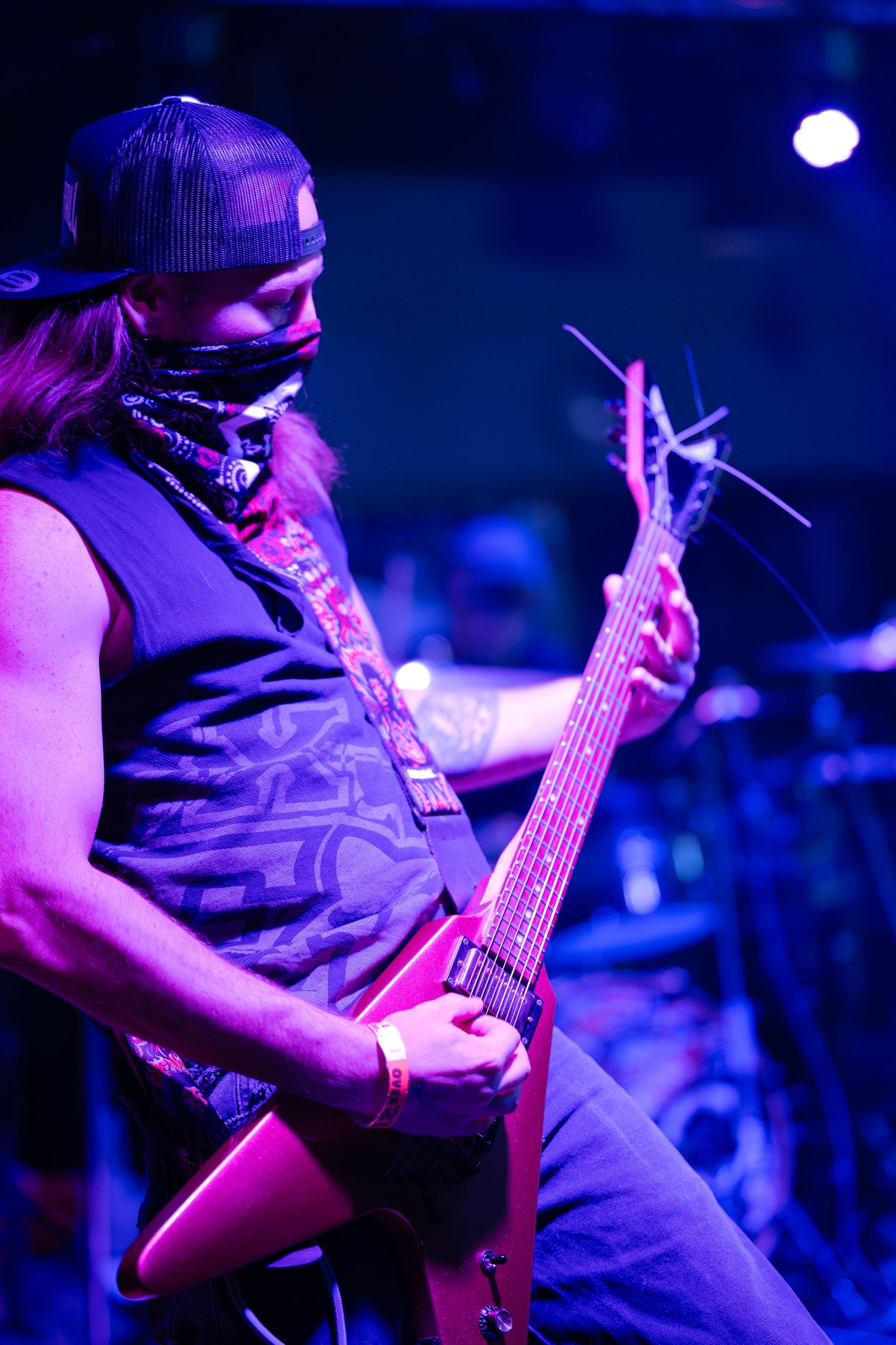 Musician performs on stage with a bass guitar under dramatic blue lighting during a live concert performance.