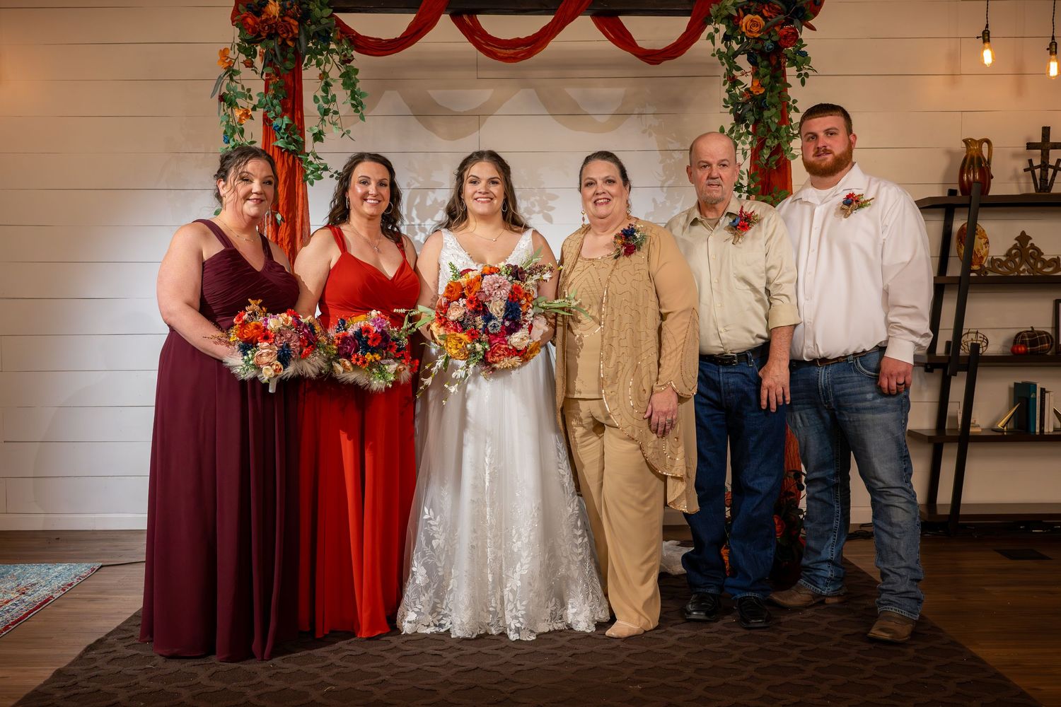 Wedding party lineup with burgundy bridesmaids dresses and white bridal gown.