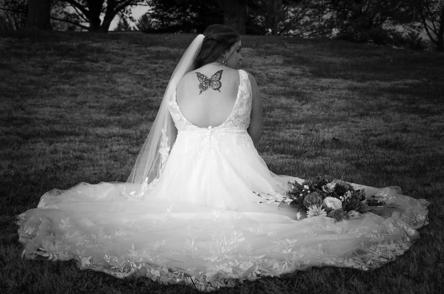 White wedding dress with intricate lace details spread beautifully on grass.