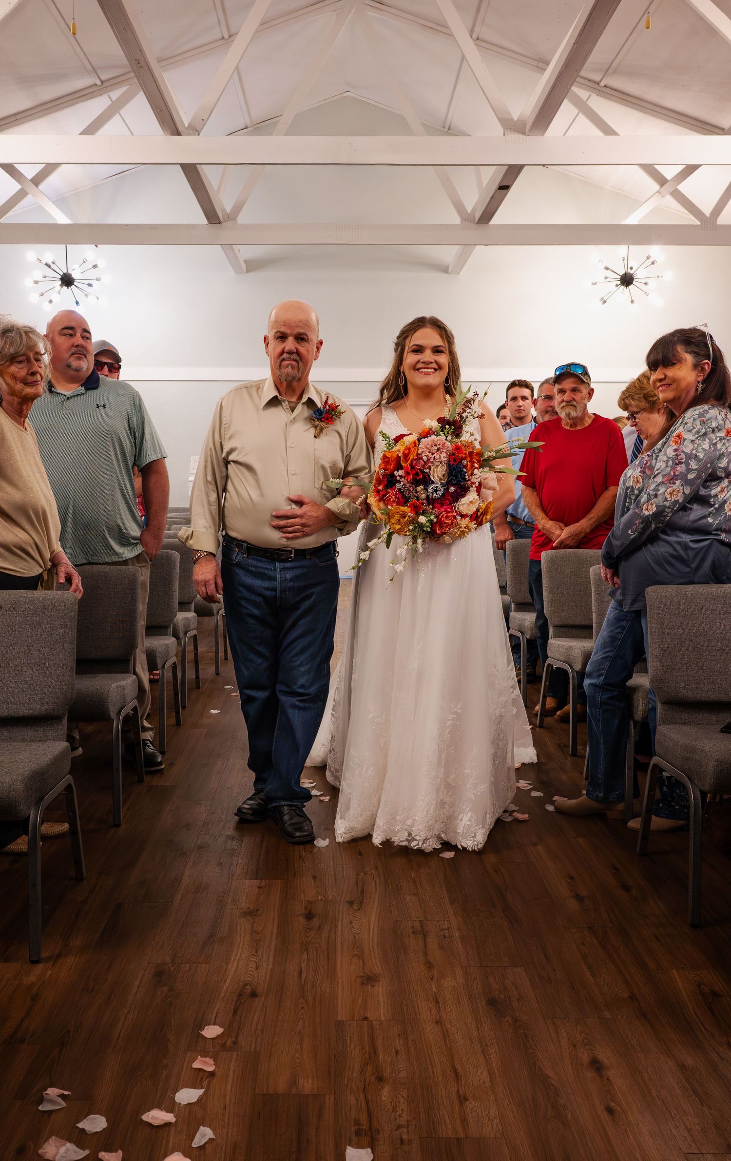 Wedding ceremony space with guests seated in rows and white lace dress visible.