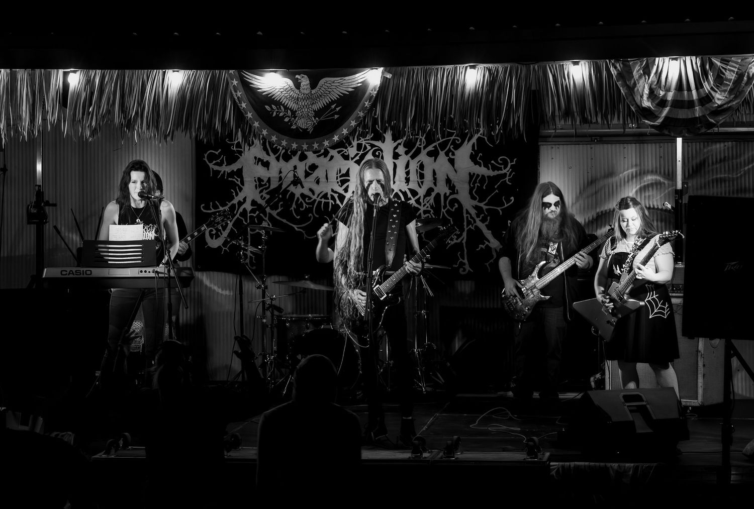 A metal band performs on stage with dramatic lighting and fog effects during an intense live concert performance.