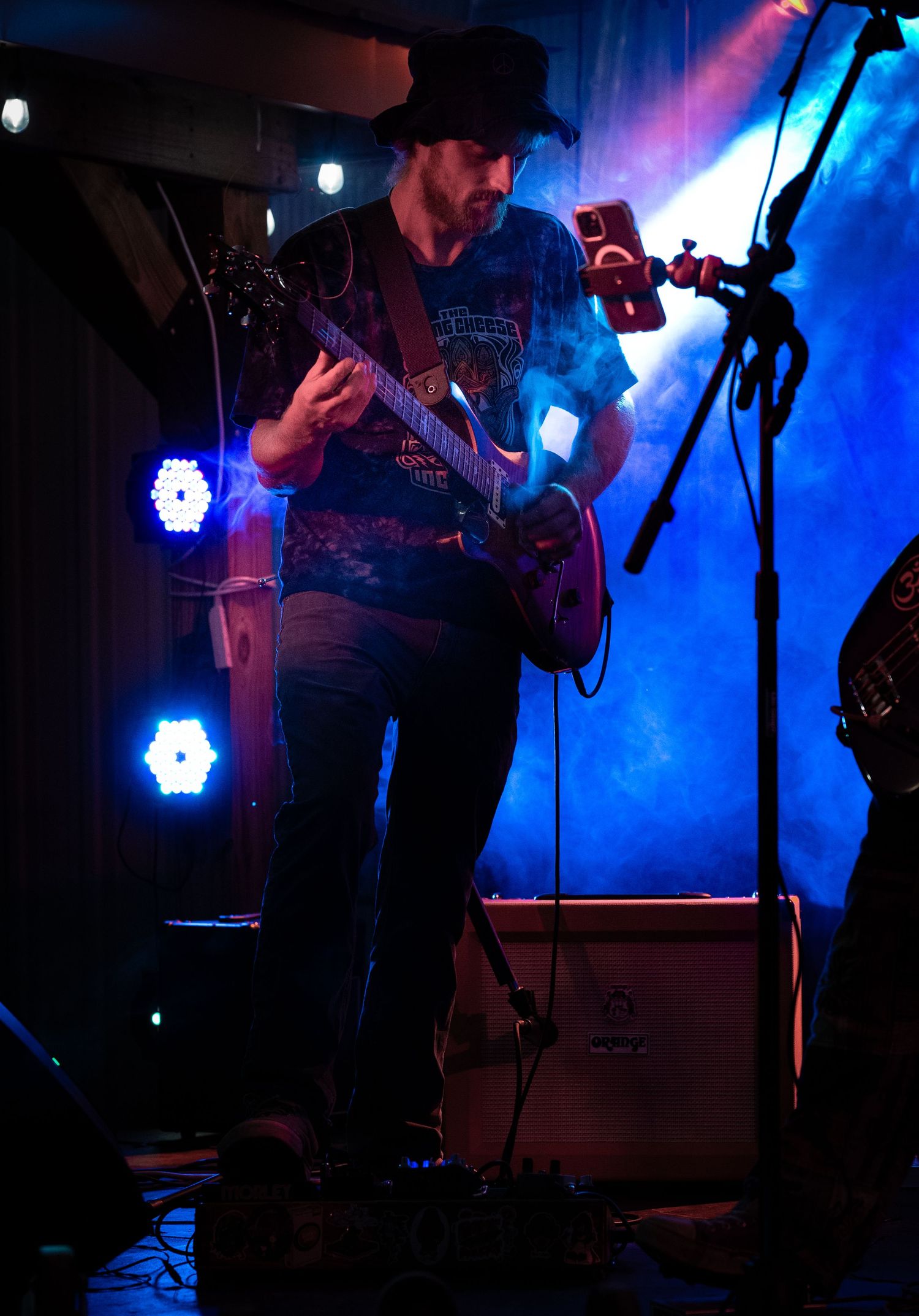Musicians perform on stage in dark lighting with dramatic blue spotlights creating an atmospheric concert environment.
