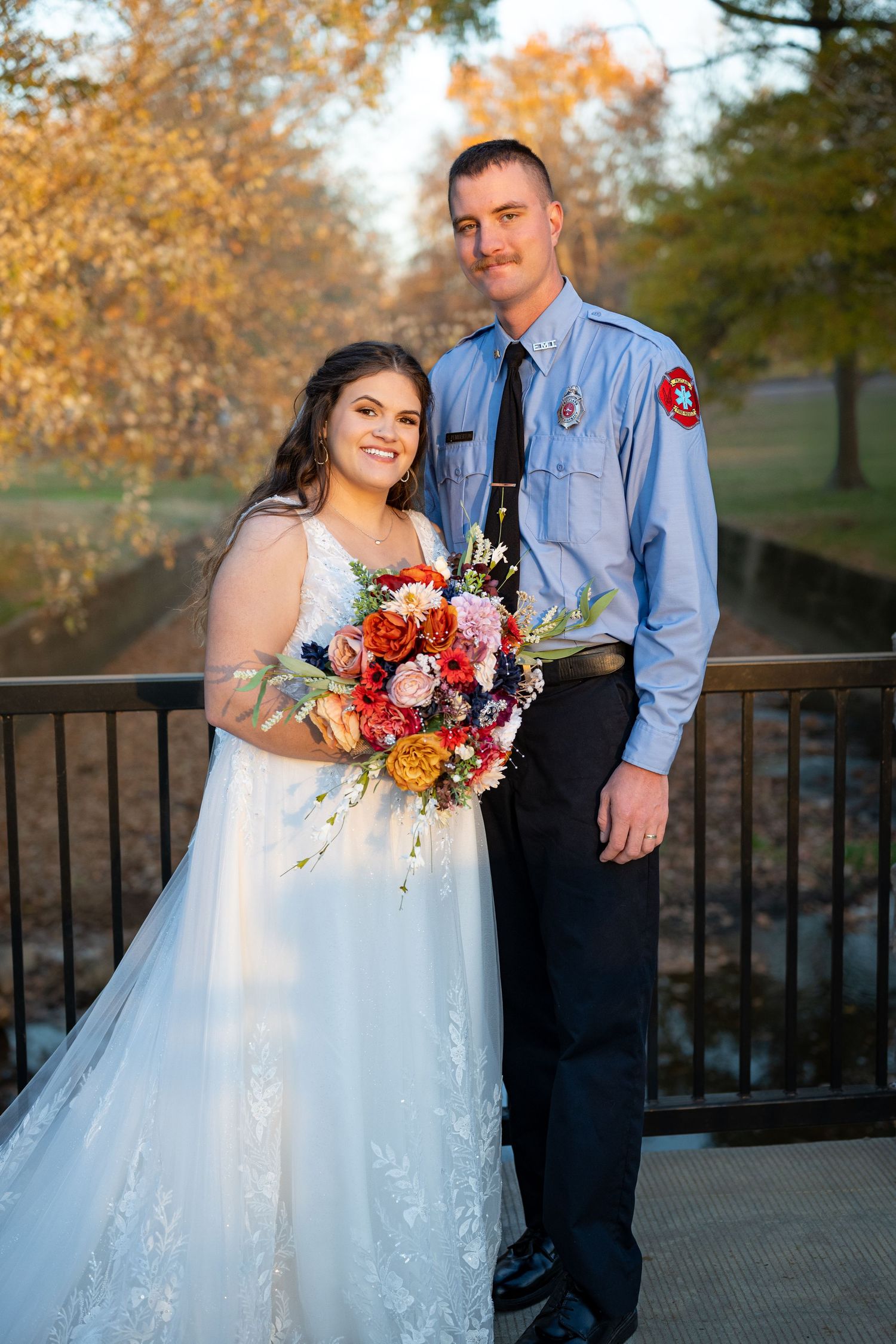 Autumn wedding photos featuring a bride in white dress with colorful bouquet on stone bridge.