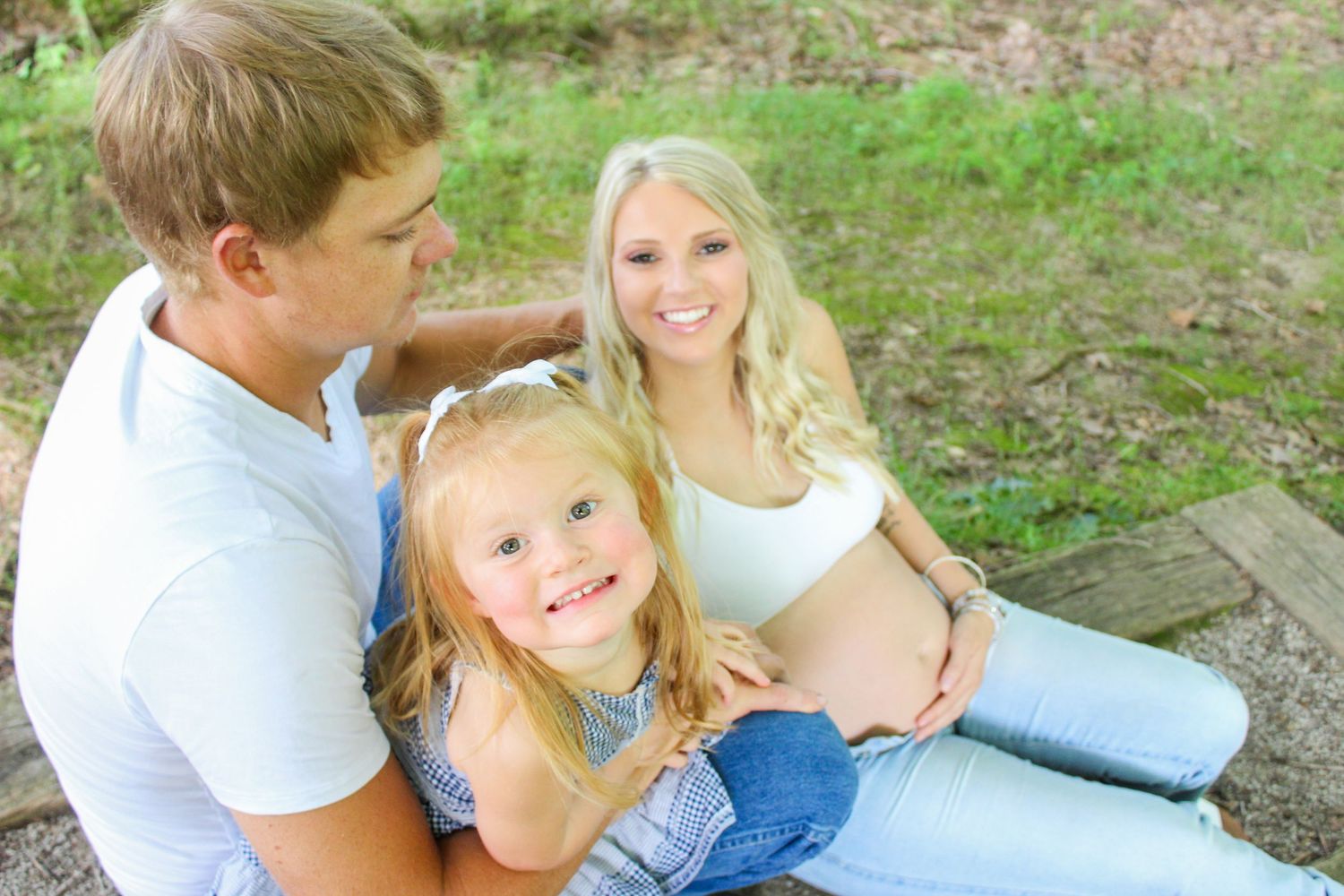 Family enjoying a tender moment together outdoors in a park setting on a sunny day.