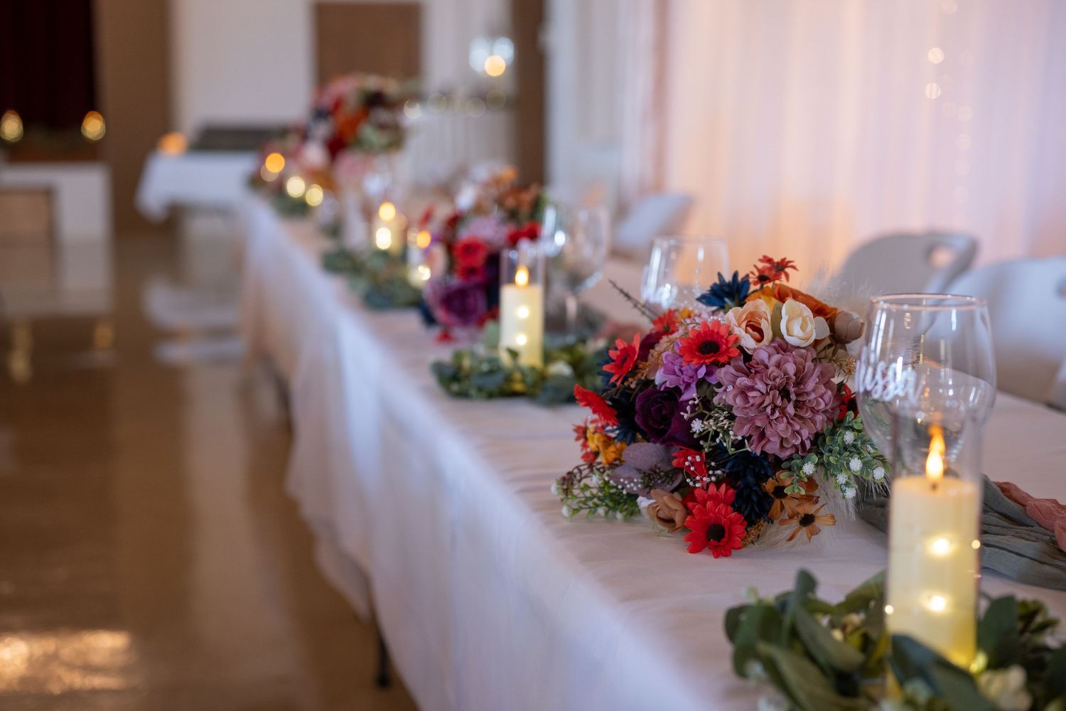 Wedding reception table with elegant floral arrangements and candle decorations.