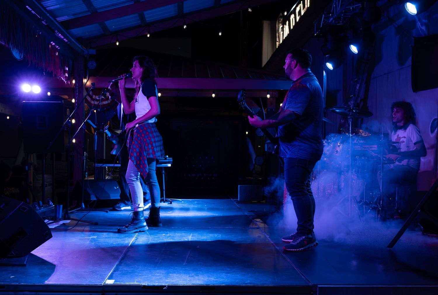 Performers on a dark stage illuminated by dramatic blue lighting during a theatrical production.