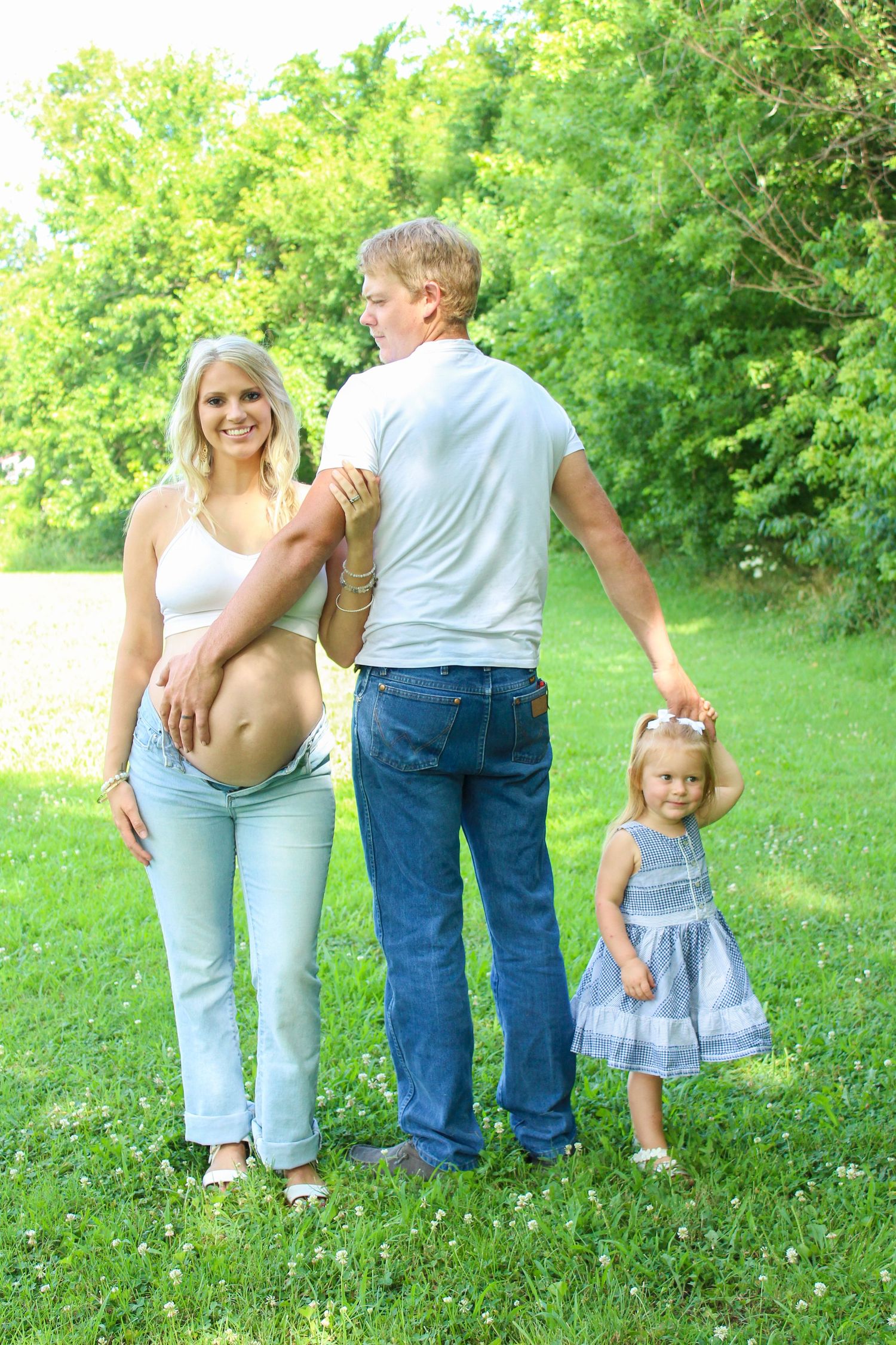 A family walks together through a lush green summer meadow holding hands on a sunny afternoon.