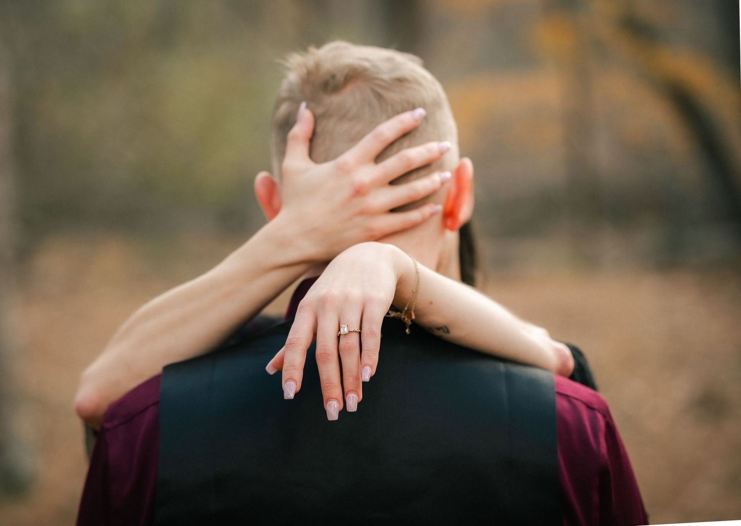 A close-up view of hands clasped together against a blurred natural outdoor background.