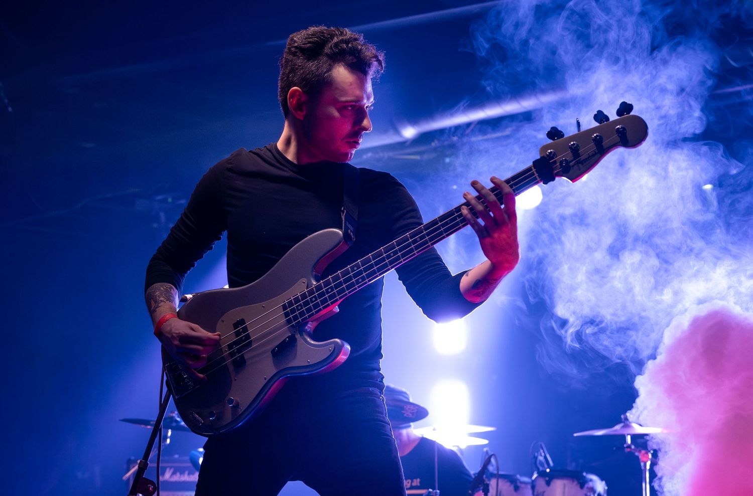 Band performs on smoky stage with dramatic blue and purple lighting effects.