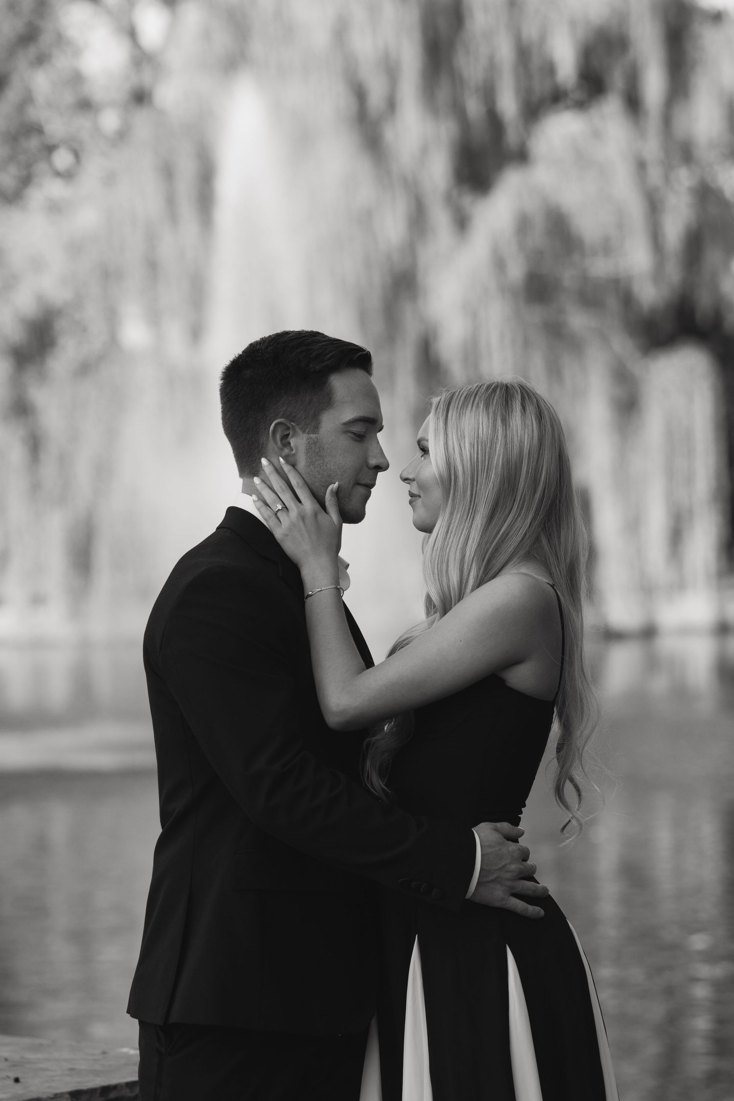 A romantic black and white photo series showing a couple embracing by a lake with Spanish moss in the background.
