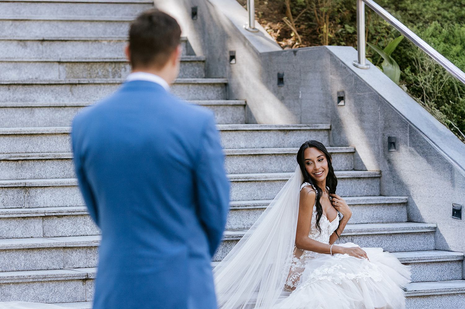 Bride sitting on marble stairs smiling at her groom during their first look at a destination wedding in Puerto Vallarta.