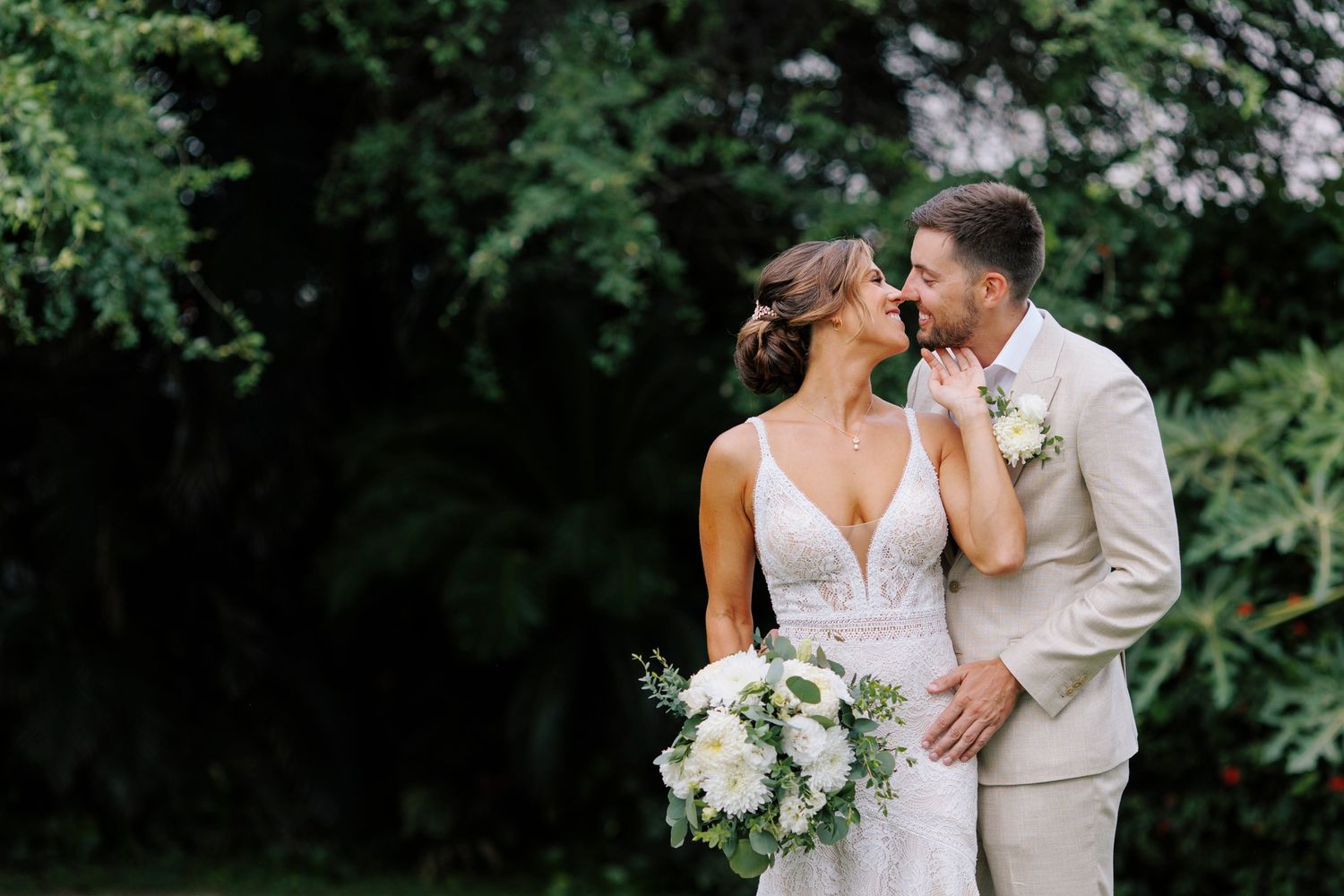 Bride and groom embracing in a lush tropical garden in Puerto Vallarta, documented with elegant natural light by José Carrillo Photography.