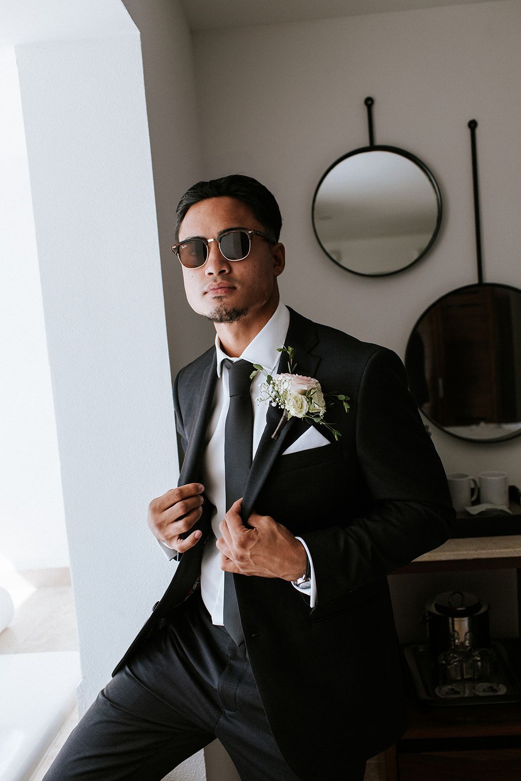 Groom wearing sunglasses and black suit getting ready for his wedding in Puerto Vallarta, by José Carrillo Photography.