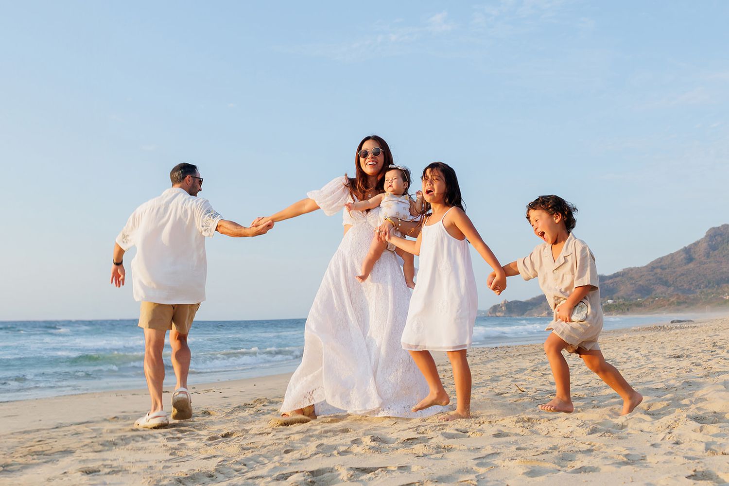 Family playing together on the beach during a sunset photo session at Conrad Punta de Mita