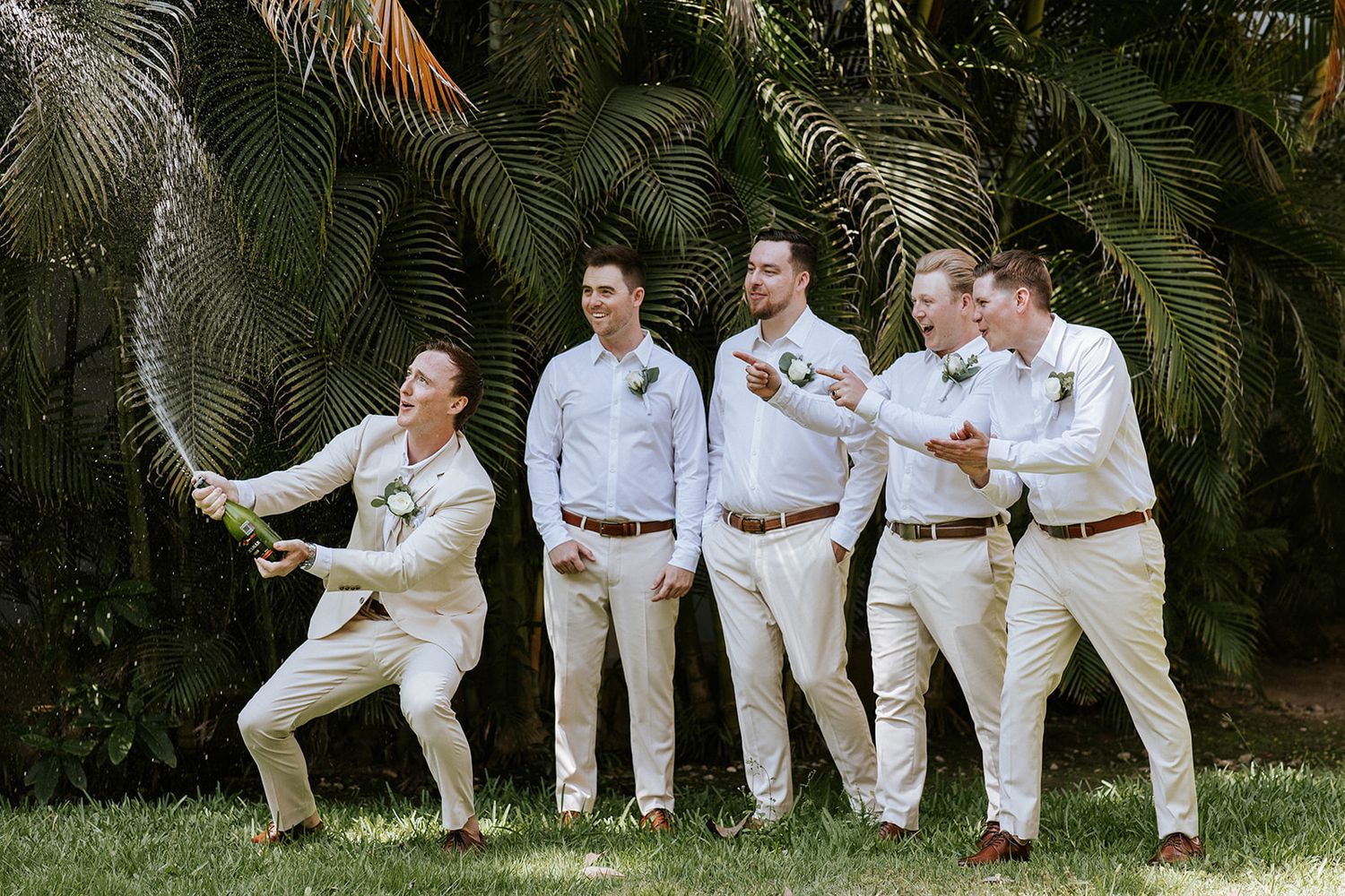 Groomsmen celebrate with champagne in a lush tropical garden before the ceremony in Puerto Vallarta, by José Carrillo Photography.