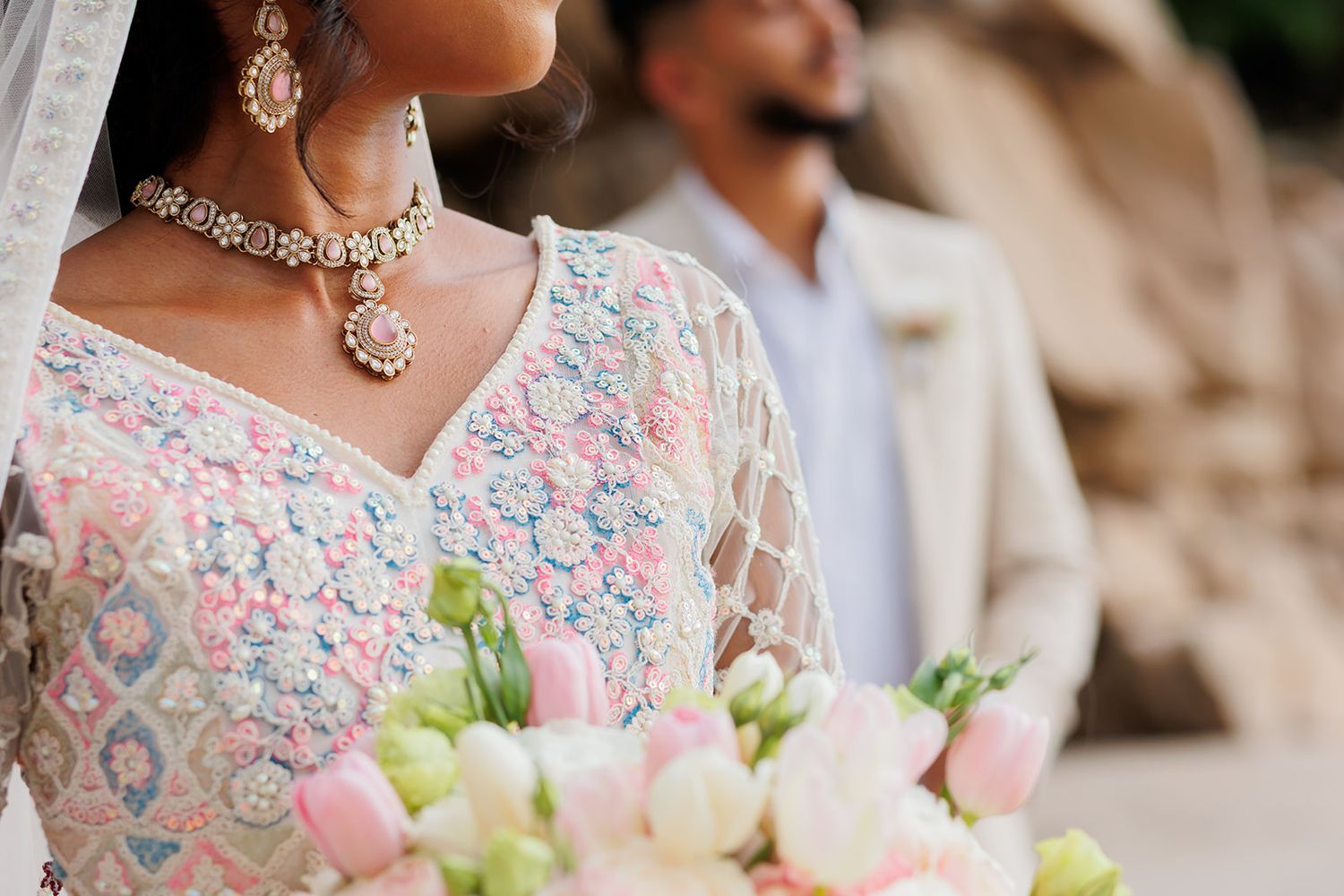 Elegant South Asian bride holding pastel flowers in Puerto Vallarta, adorned in traditional jewelry and lace, captured by José Carrillo Phot