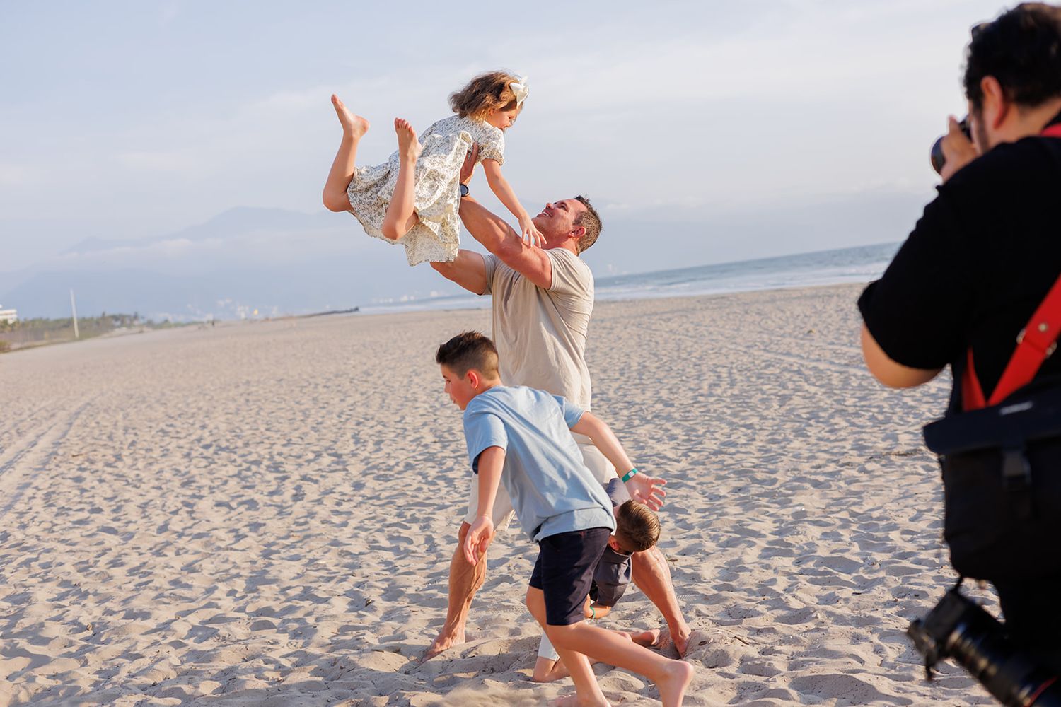 Father lifting his daughter in the air during a playful family beach photo session in Puerto Vallarta