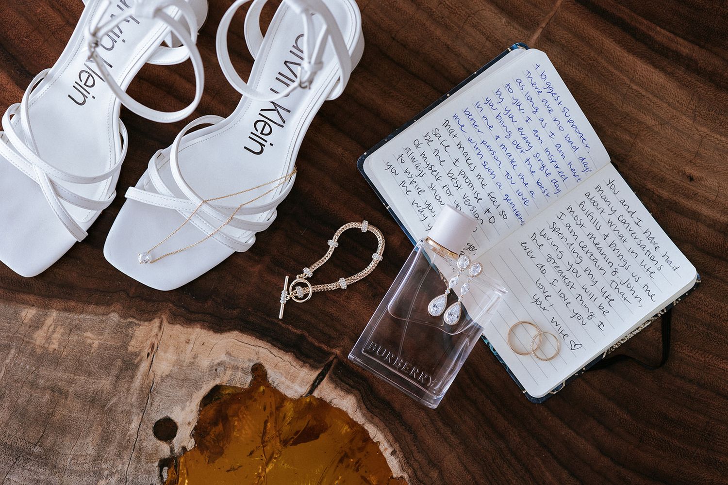 Elegant bridal flatlay with white Calvin Klein heels, Burberry perfume, jewelry, and love notes captured by José Carrillo in Puerto Vallarta