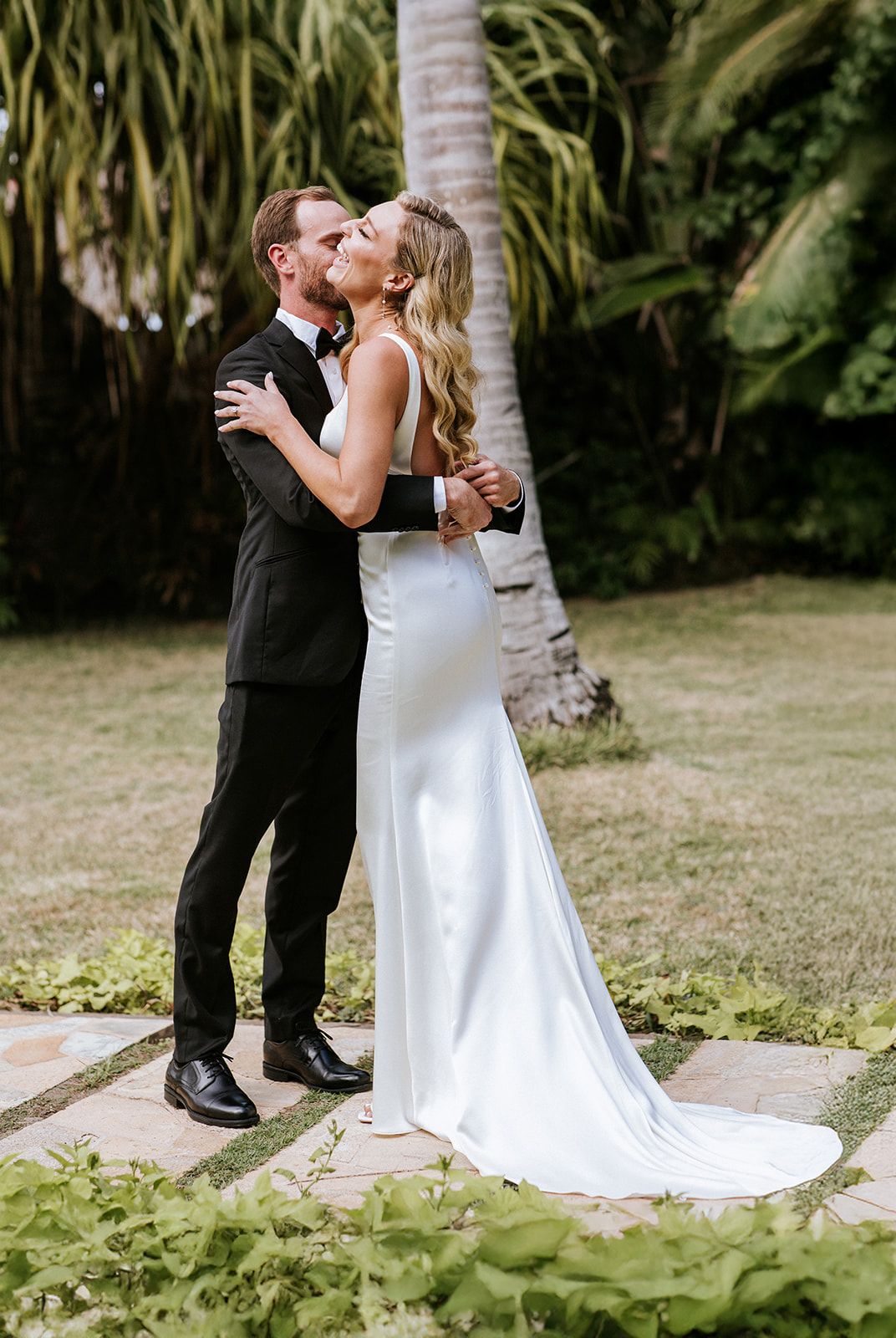 Groom embraces bride during their emotional first look in a tropical garden in Puerto Vallarta, by José Carrillo Photography.