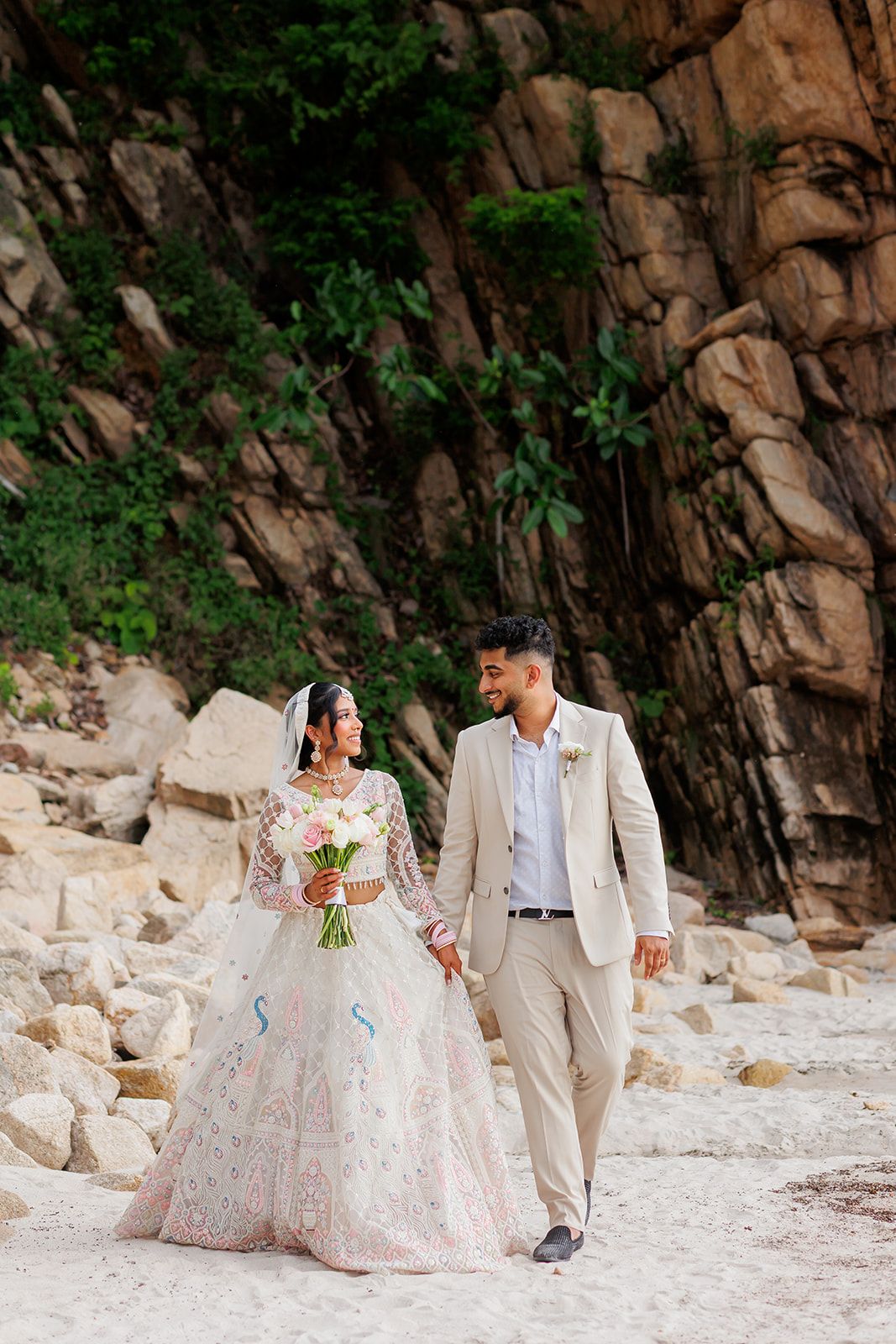 Bride and groom walking hand in hand during an elegant Indian beach wedding in Puerto Vallarta, captured by José Carrillo Photography.