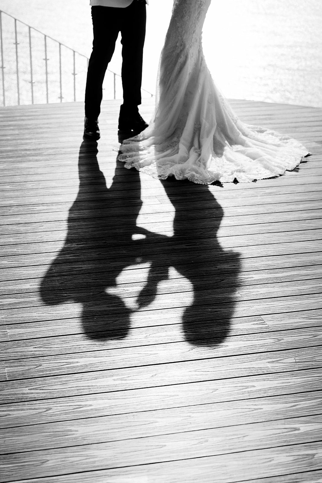 Artistic black and white wedding portrait showing the couple’s shadow on wooden deck by the ocean in Puerto Vallarta, by José Carrillo.